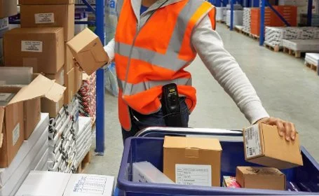 Person in safety vest packing boxes in a warehouse