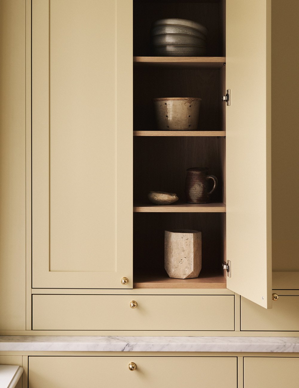 Yellow Shaker kitchen cupboard with a natural light oak interior.