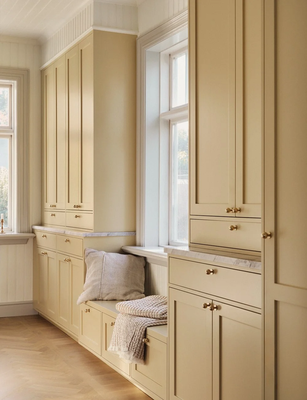 Bespoke built-in window seat with concealed storage beneath a kitchen window.