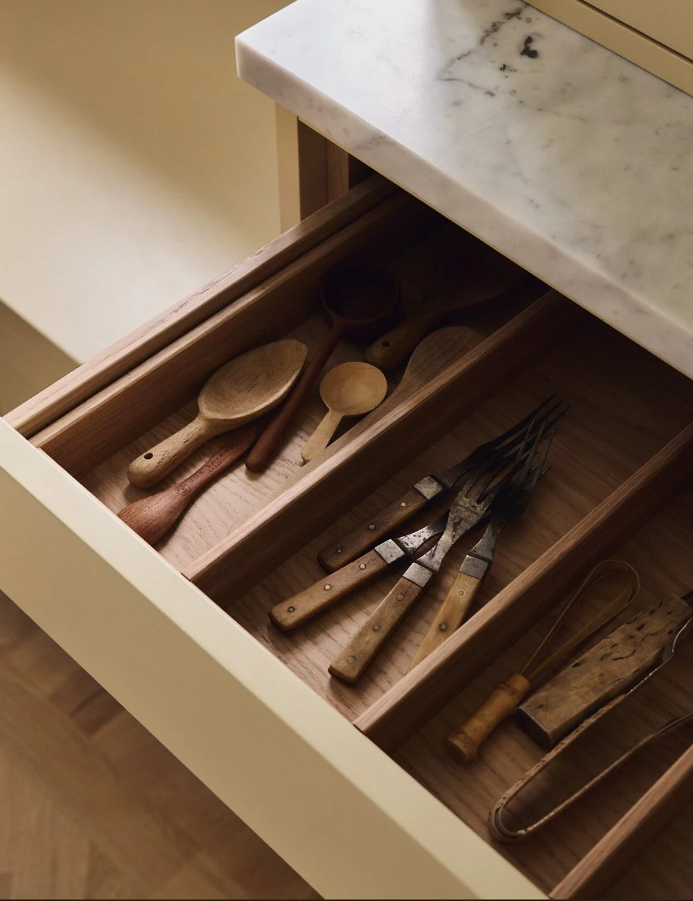 Bespoke oak cutlery inserts fitted inside a kitchen drawer, with individual compartments for cutlery.