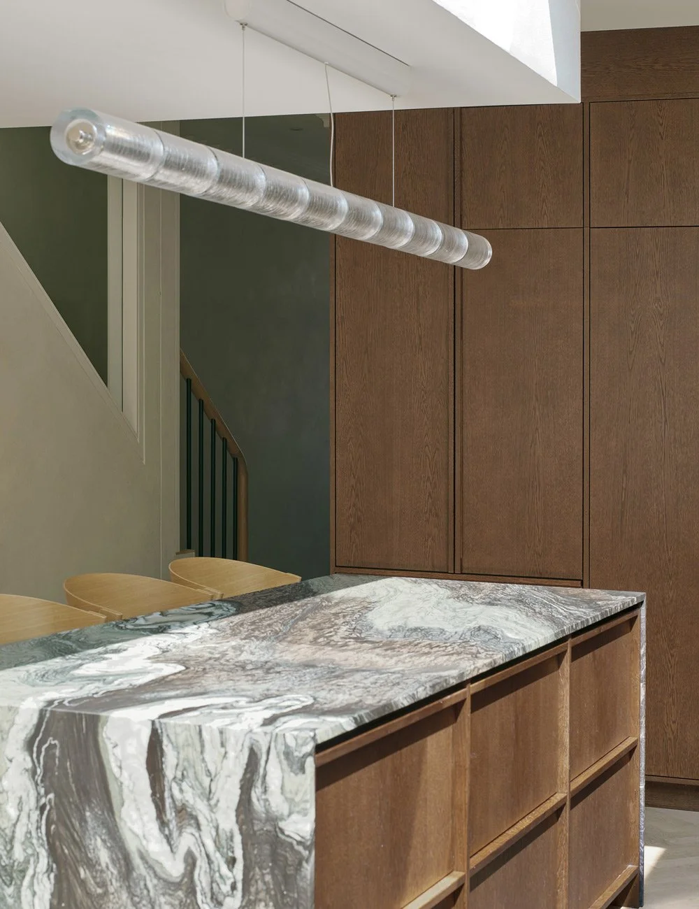 Bespoke oak kitchen cabinetry concealing Fisher & Paykel appliances, with a Flos pendant above the island.