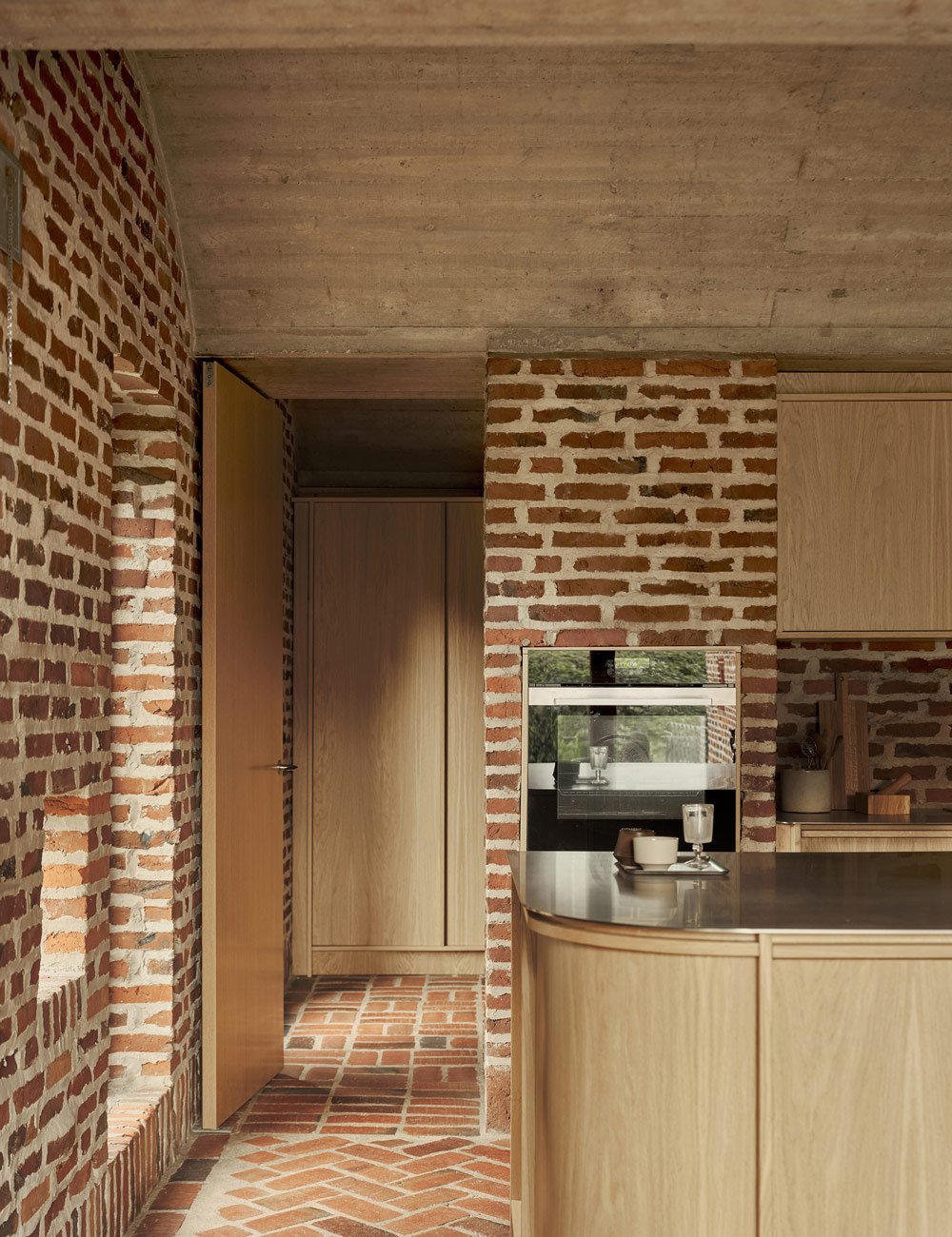 Light oak kitchen with island and a view into the utility room with bespoke fitted cabinetry.