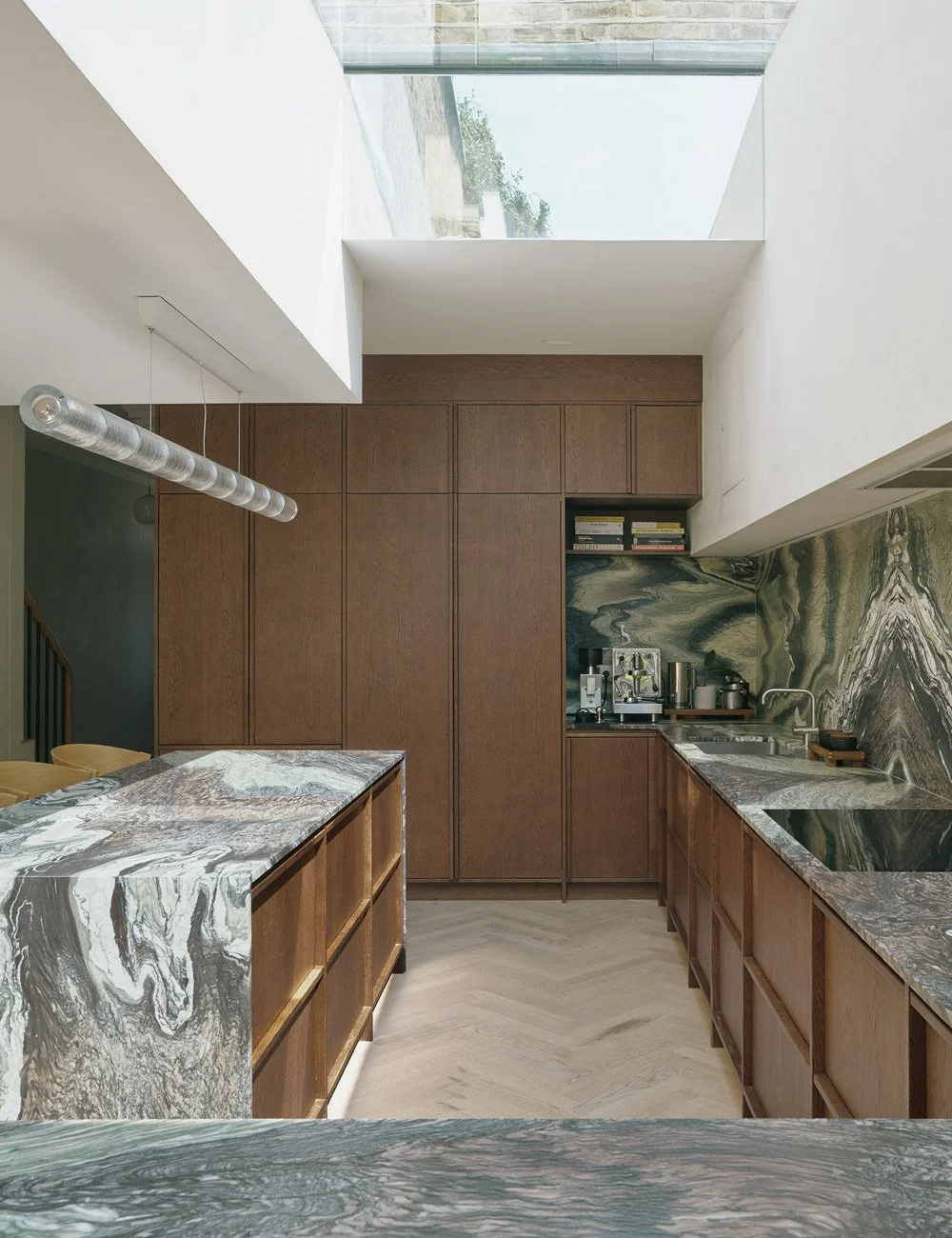 Dark oak kitchen cabinetry paired with green marble and white walls in a Scandinavian-inspired London home.