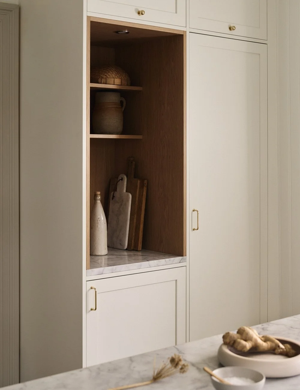 Built-in kitchen coffee station with open oak shelving and brass handles on the surrounding cabinetry.