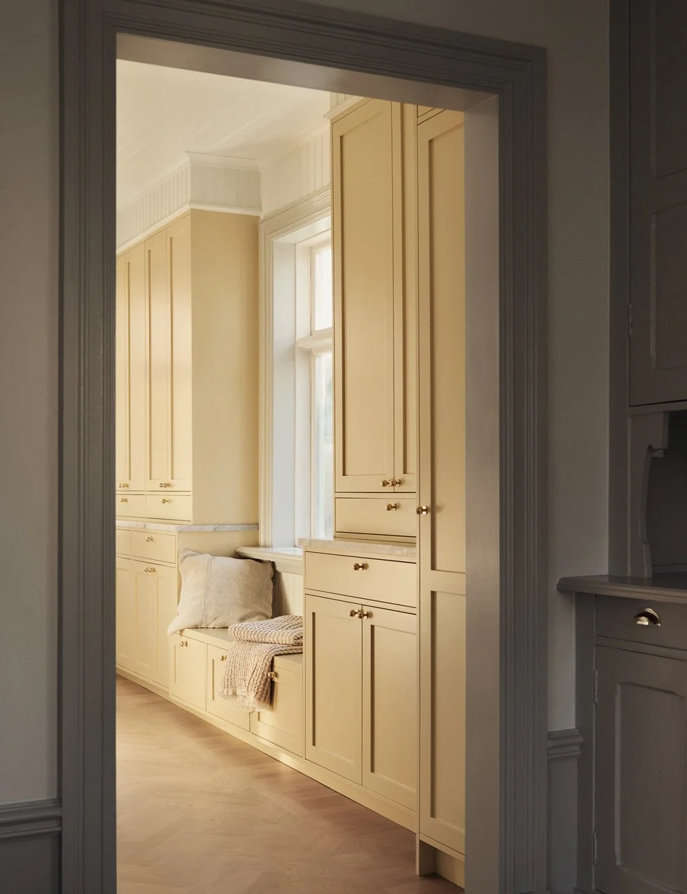 Traditional kitchen with bespoke soft yellow Shaker cabinetry, viewed from the adjoining dining room.