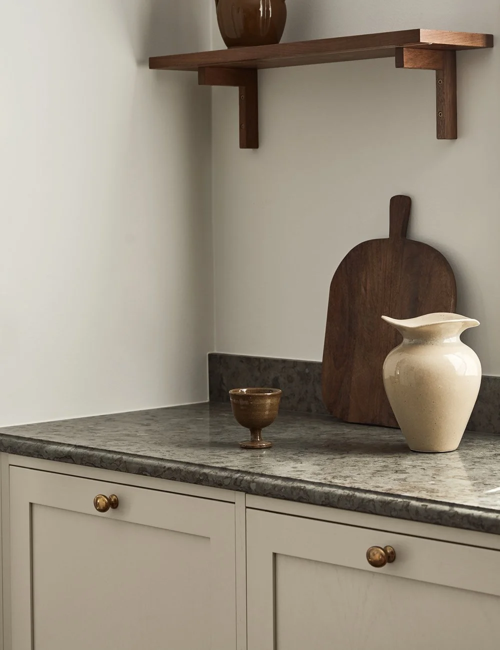 Classic beige Shaker kitchen with grey Kinnekulle limestone worktop, profiled edge and brass knobs.