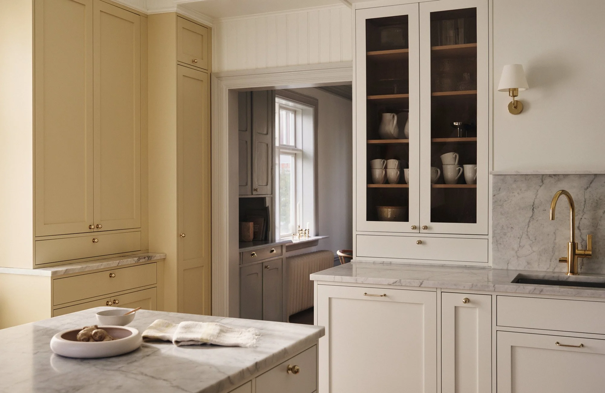 Soft white Shaker kitchen cabinets with an Ilve cooker, Decosteel sink and built-in display cabinet.