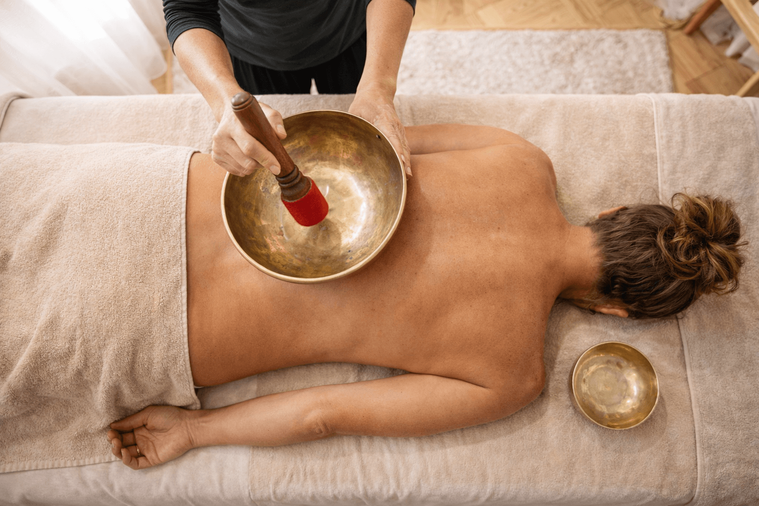 Une femme reçoit un massage avec des bols tibétains pour la relaxation.