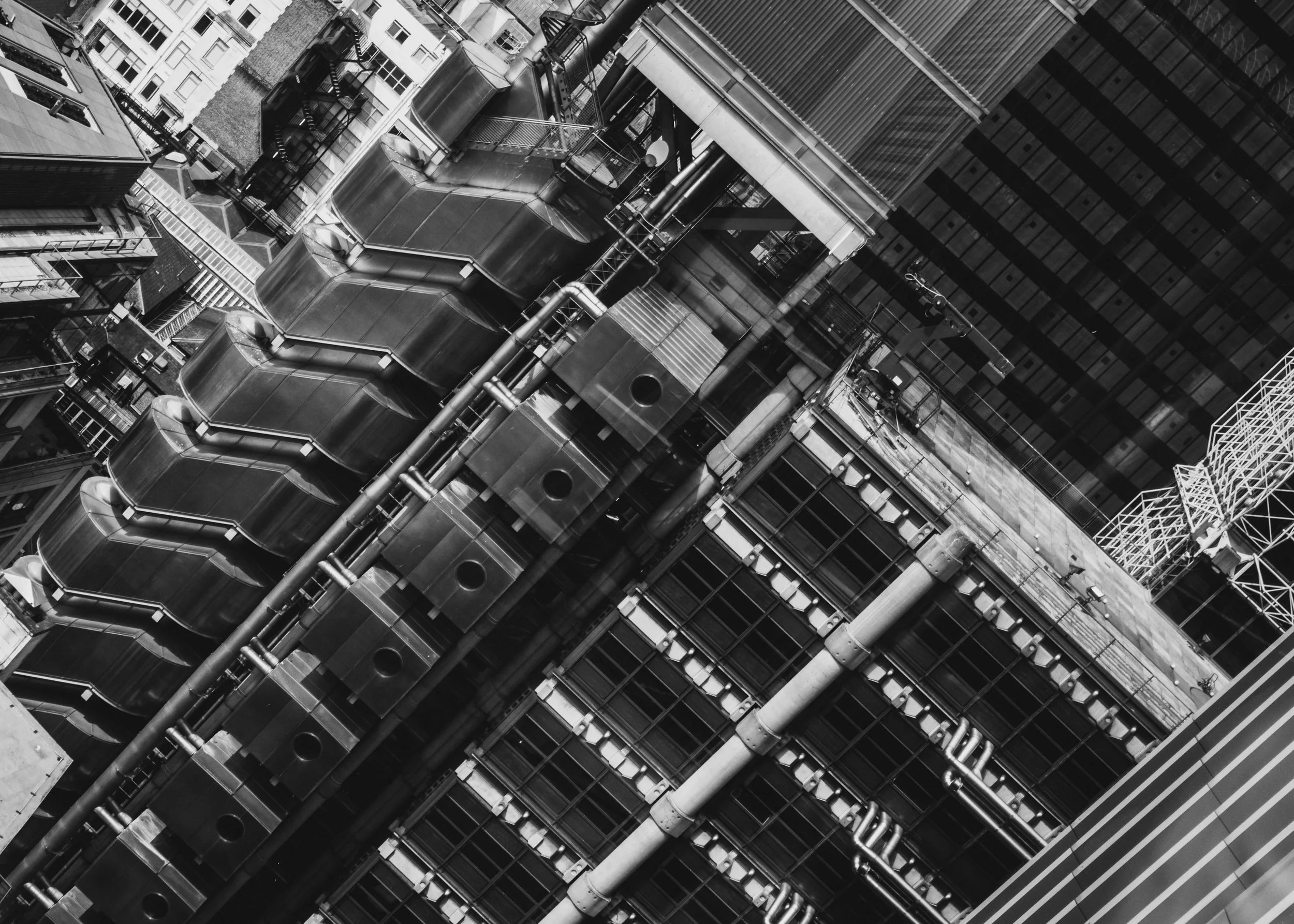 A black and white aerial view of a city skyscraper with visible mechanical and structural details.