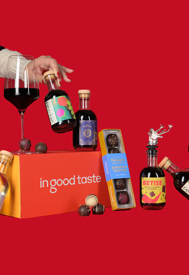 Assorted chocolate truffles and bottles of syrup on a red background, with a red box that says 'in good taste'.