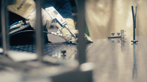 A scientist using a pipette to manipulate a liquid on a laboratory workbench.