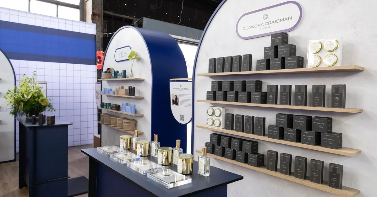 The interior of a large trade show booth. There are two counters with products on shelves just behind them.