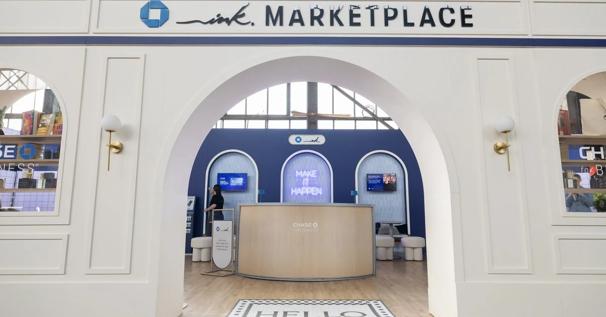 A white archway leading into a large trade show booth for Chase bank. There is a large "Hello" welcome mat on the ground.