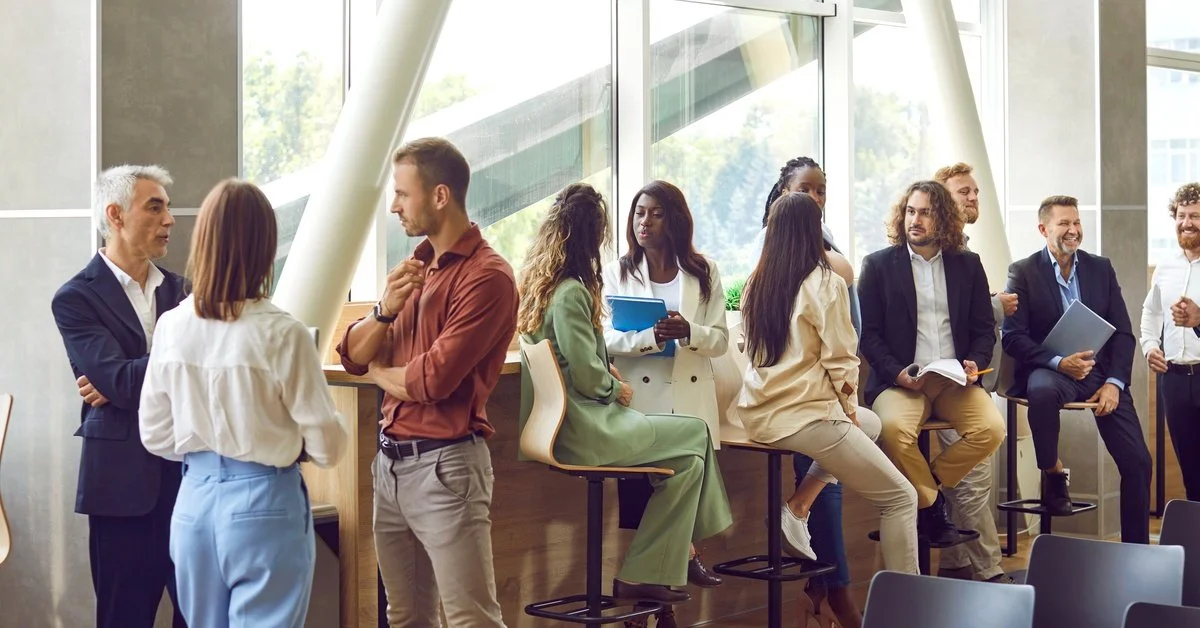 A lineup of diverse businesspeople all in professional dress lined up against a counter in front of a large window.