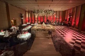 The interior of a fancy ballroom. There are circular tables and a black and white checkered dance floor.