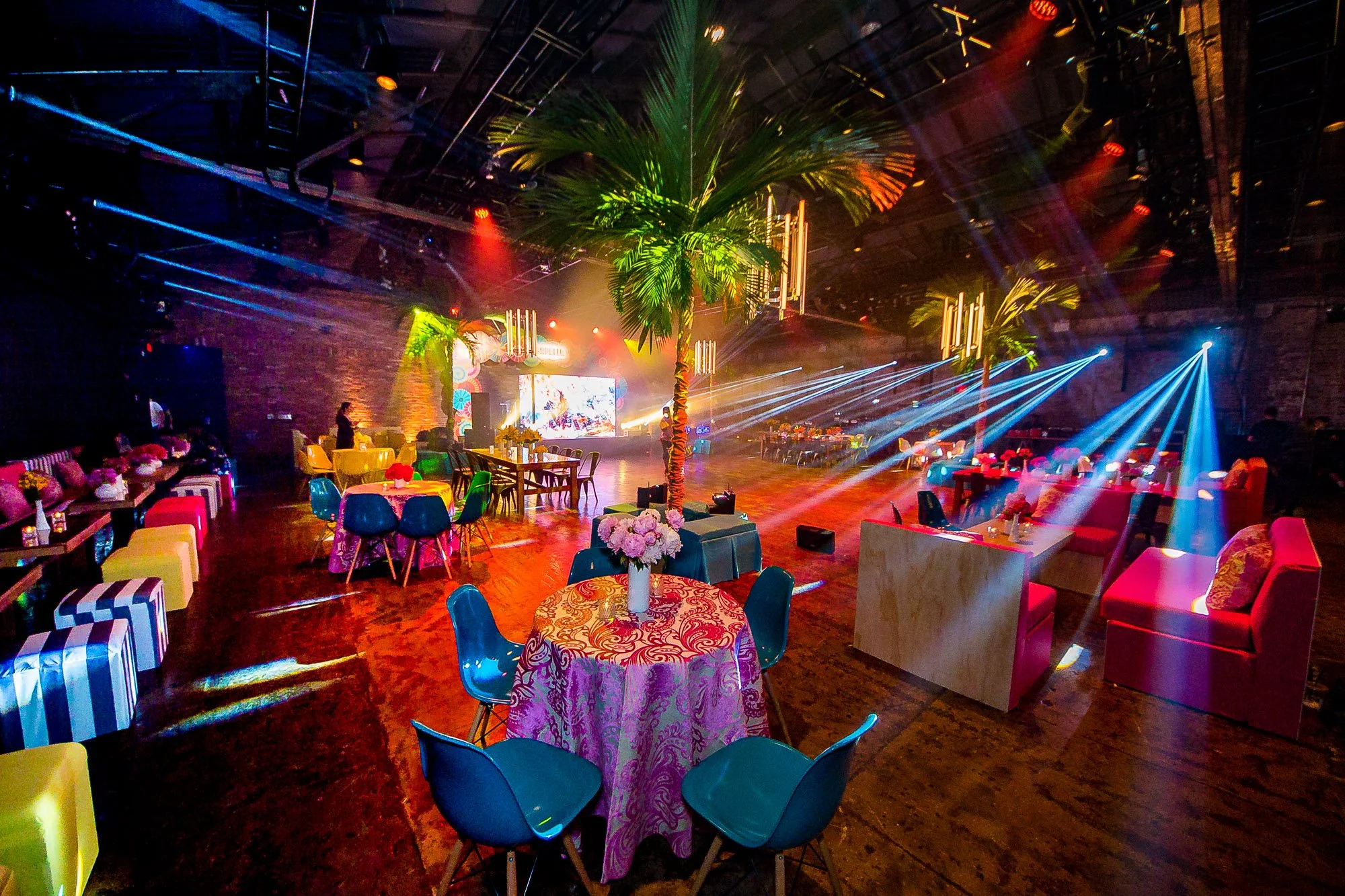 A wedding reception room set up for a party with a large dance floor and tables set up all around it.