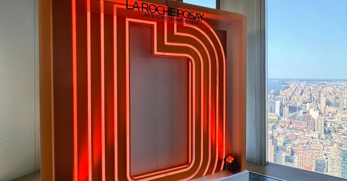 An illuminated display featuring red neon light elements, positioned next to floor-to-ceiling windows overlooking a city skyline.