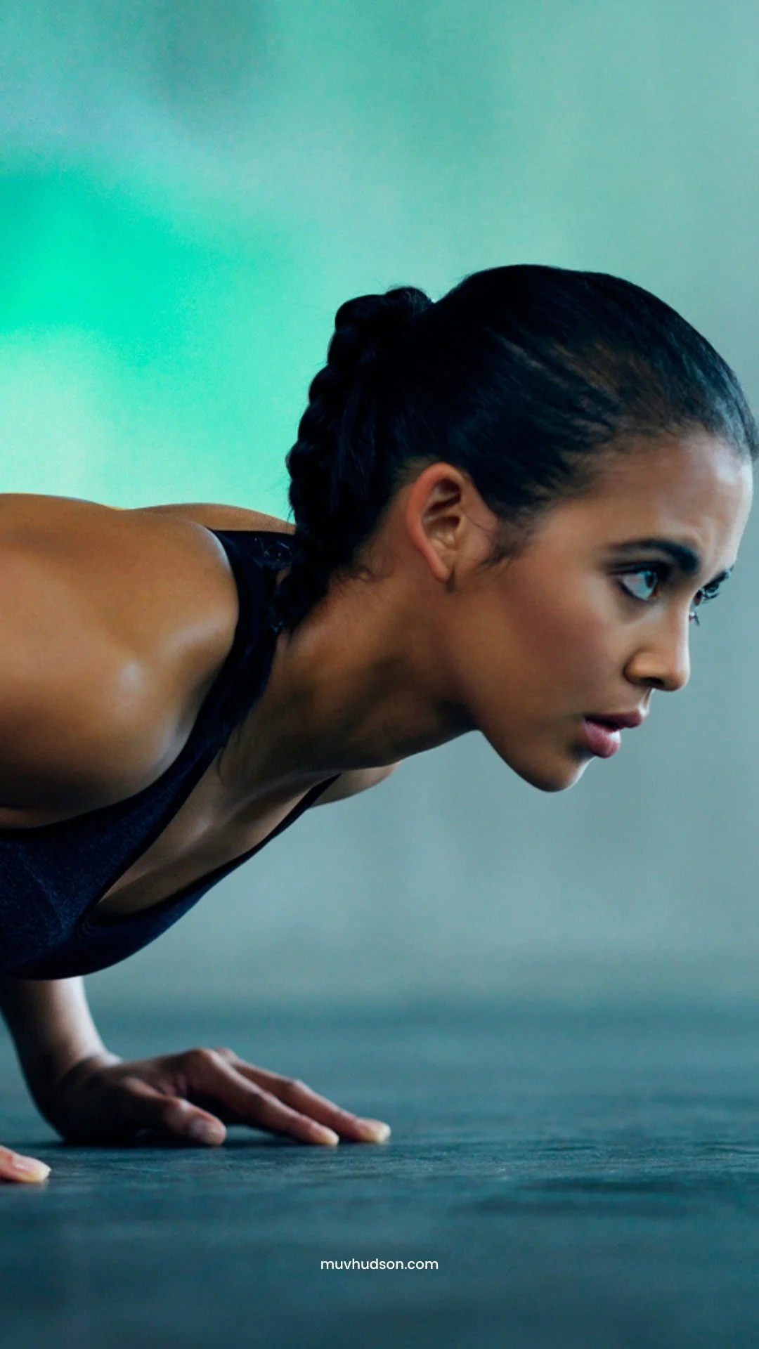 A woman performing a push-up exercise on a gym floor with focused expression.