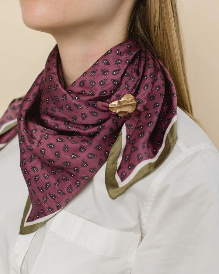 The problem with scarves? They never stay put.
You tie them perfectly, then five minutes later they're slipping, sliding, or looking sad and droopy. We've all been there.
Here's the fix: a brooch 💫
Pin it at the knot, on the side, wherever feels ri