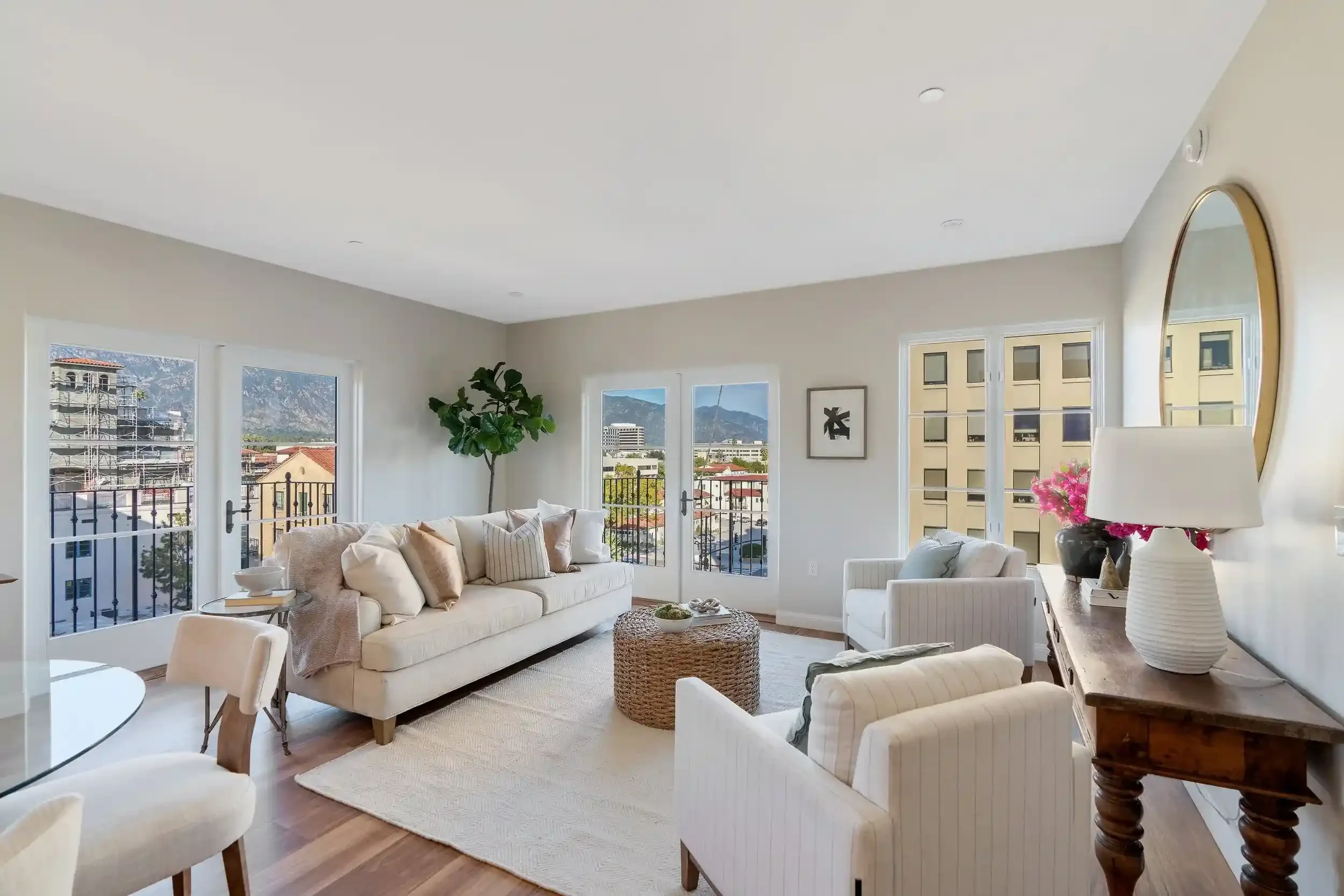 Bright living room at Brantwood senior apartments in Pasadena’s Playhouse Village, featuring French doors, balcony views, neutral furnishings, wood-style flooring, and mountain