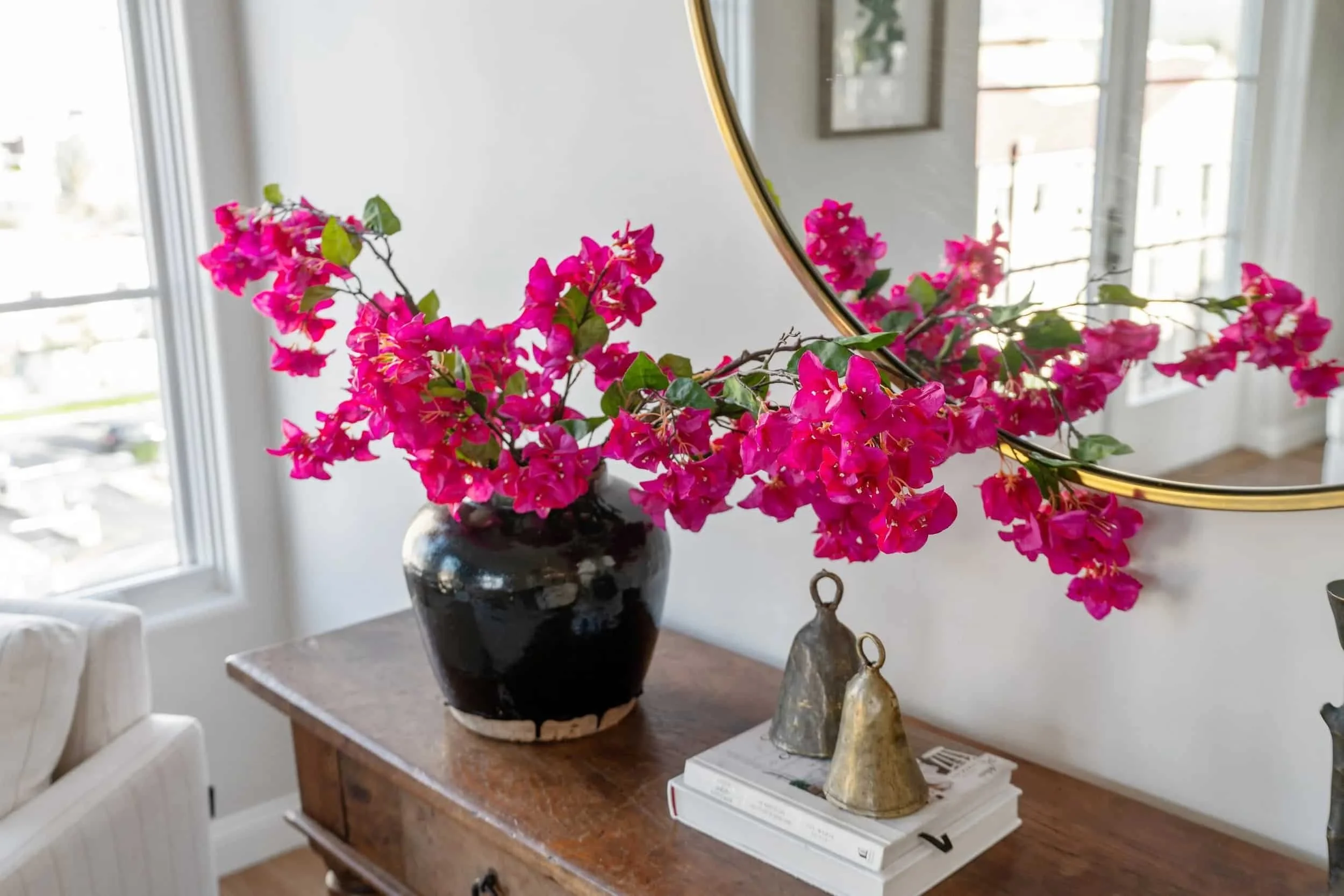 Pink floral arrangement in a luxury apartment at Brantwood senior apartments in Pasadena’s Playhouse Village, displayed on a wood console table with a round mirror.