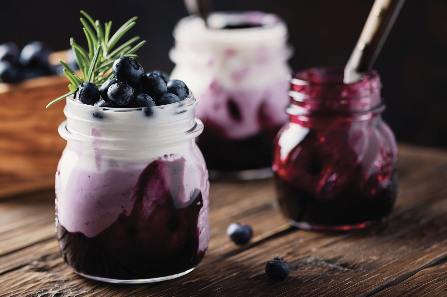 Flavor Producers - Glass jar with blueberry jam layered beneath yogurt and topped with fresh blueberries, representing fruit and dairy flavors.