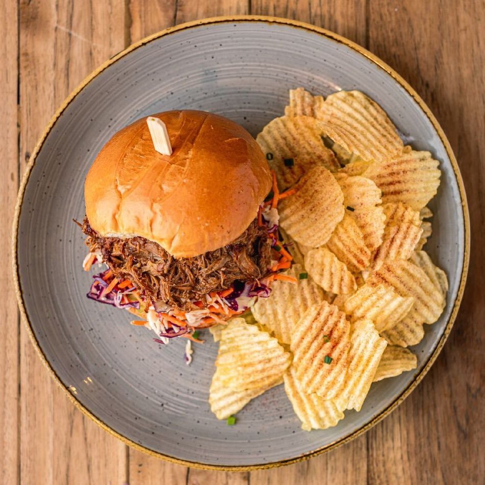 Introducing the newest member to Two Siisters Pantry! Pulled pork, crunchy coleslaw, house made smoky sauce on a soft milk bun served w/ a side of potato crisps! Now this is a dish that&rsquo;ll never become boaring! 🥓 #twosiisterspantry #TSP