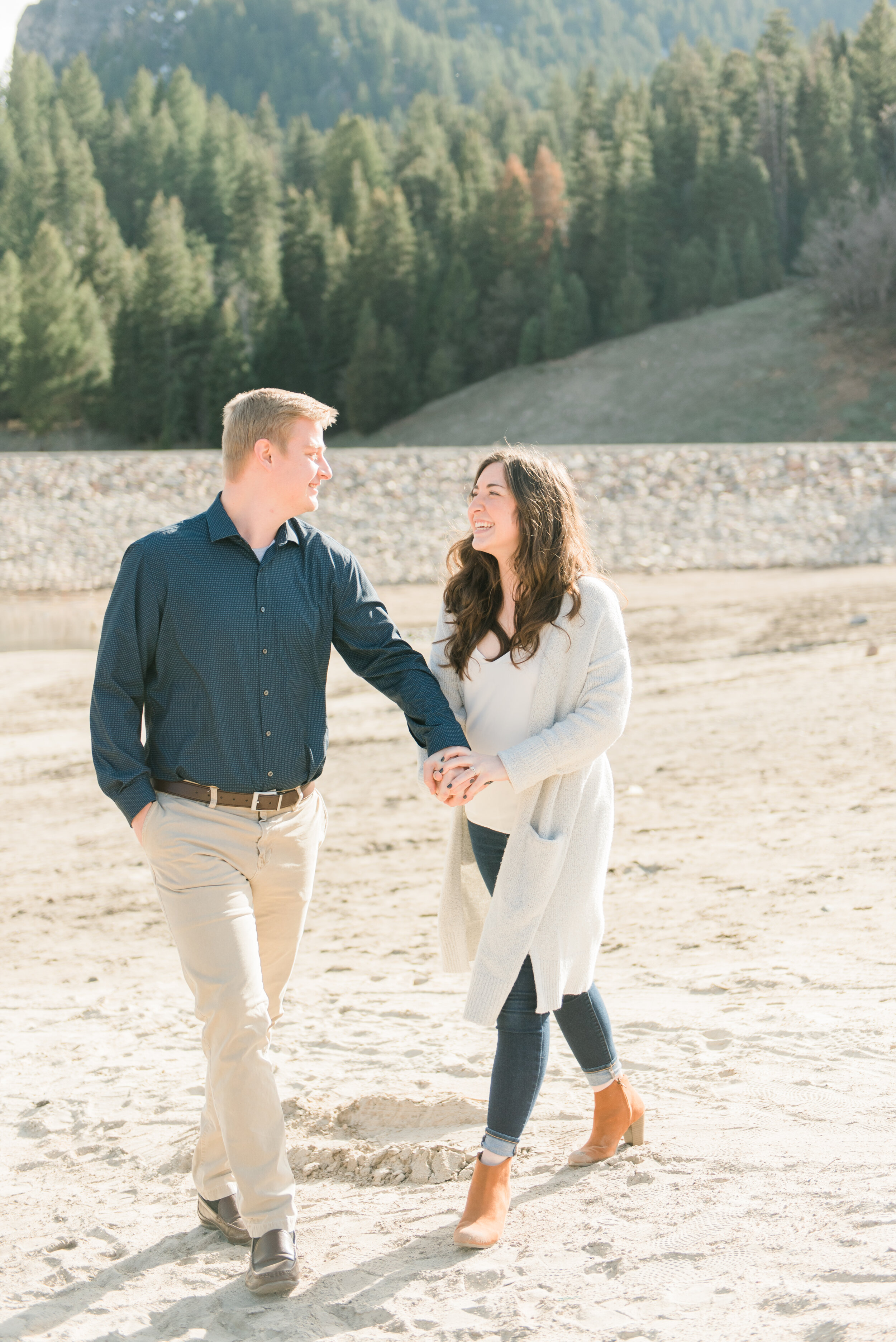 Future bride and groom share a stroll together in this mountain feel engagement shoot in Maryland by Jacquie Erickson Photography. Mountain escape lake white sweater blue button down shirt semi formal wear outfit inspiration happy couple engagements