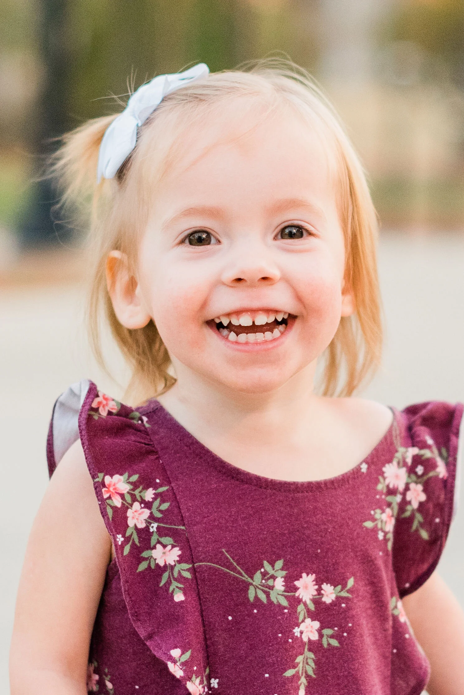  An adorable close-up shot of this smiley little girl during her family pictures with Jacquie Erickson Photography in Atlanta, Georgia. Floral maroon dress blonde hair blue bow little girl smile Baltimore family photographer #jacquieericksonphotograp