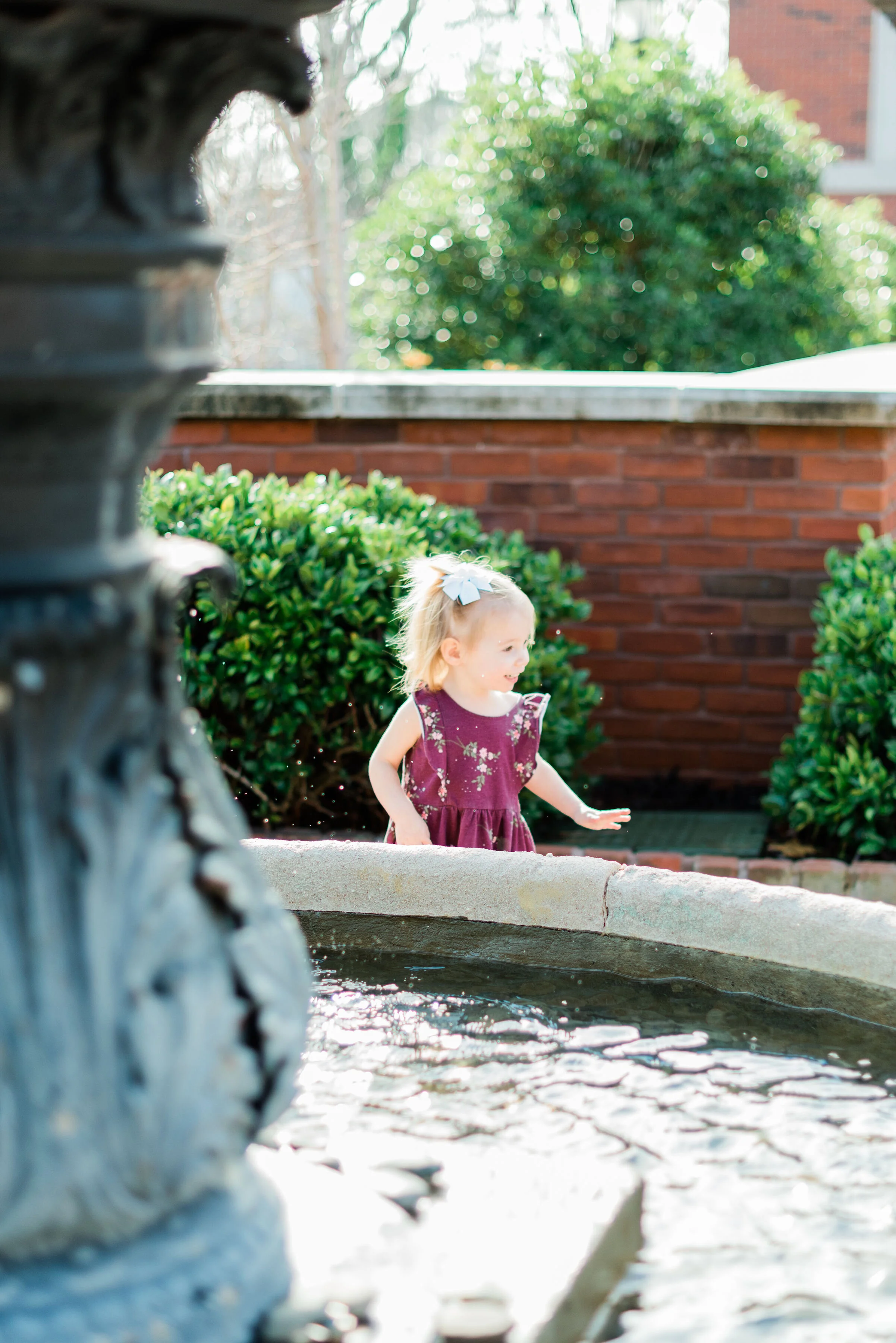  An adorable little girl plays around the fountain during family pictures in Atlanta, Georgia with Jacquie Erickson Photography. Little girl playing water fountain feature candid moment captured Baltimore maryland family photographer outdoor autumn f