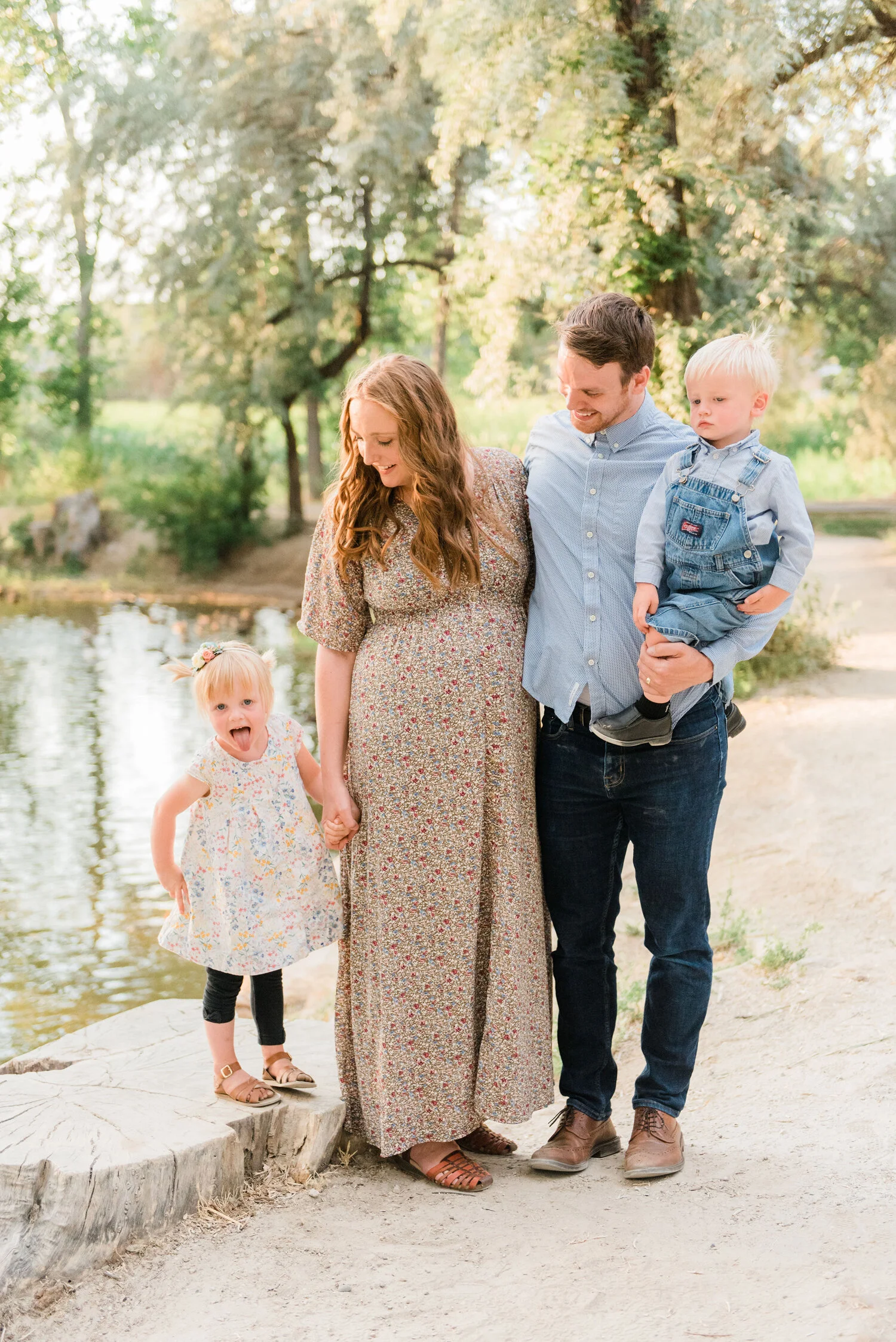  While posed next to a duck pond in Columbus, Maryland, Jacquie Erickson Photography captures this expectant family of five holding hands. mom looks down at daughter for family photos, maternity photo session baltimore maryland, professional maternit