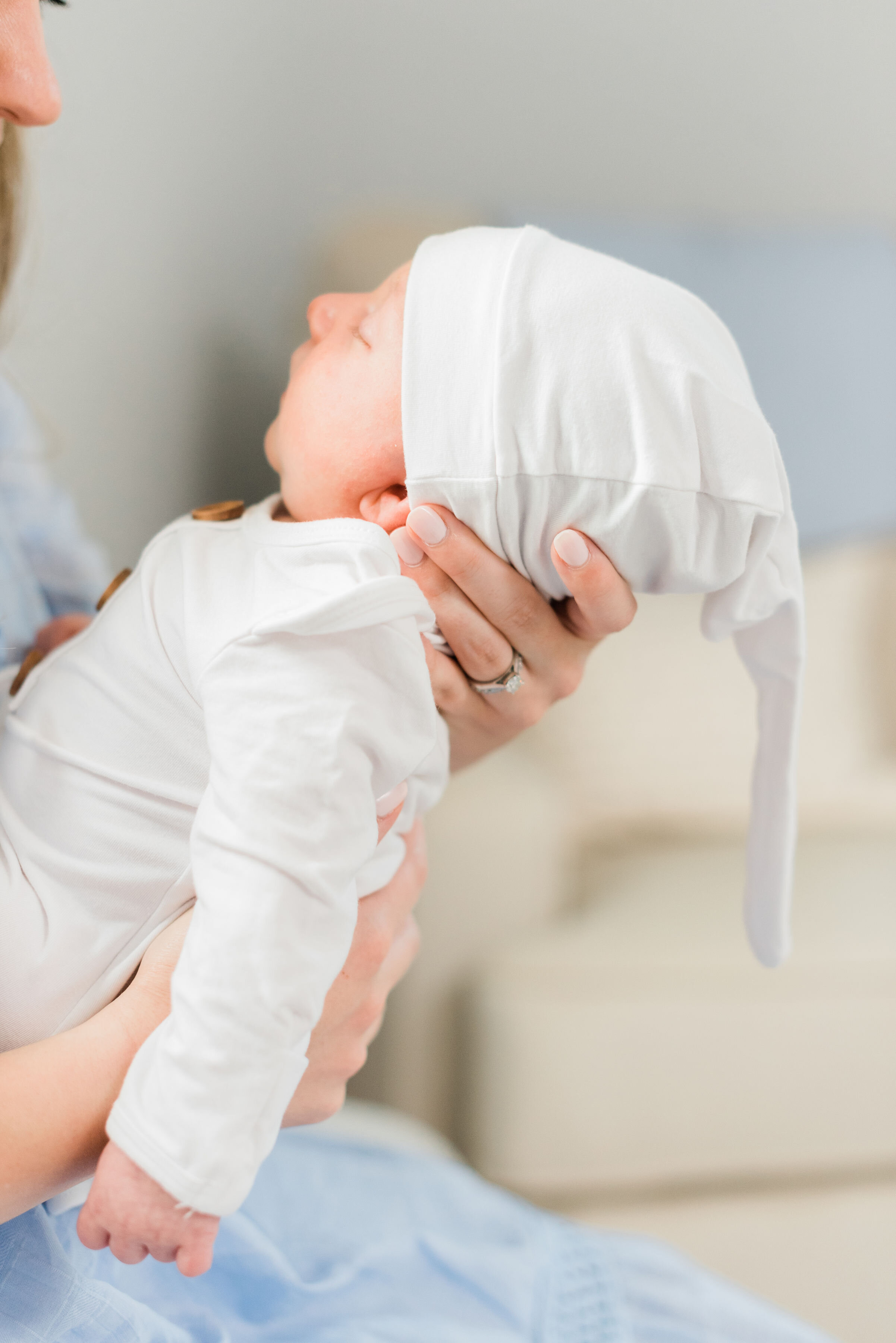  During this at-home newborn photoshoot, Baltimore, Maryland photographer, Jacquie Erickson Photography captres this newborn’s profile as this mother holding his in her forearms. mother holding newborn with forearms upright sleeping newborn profile p