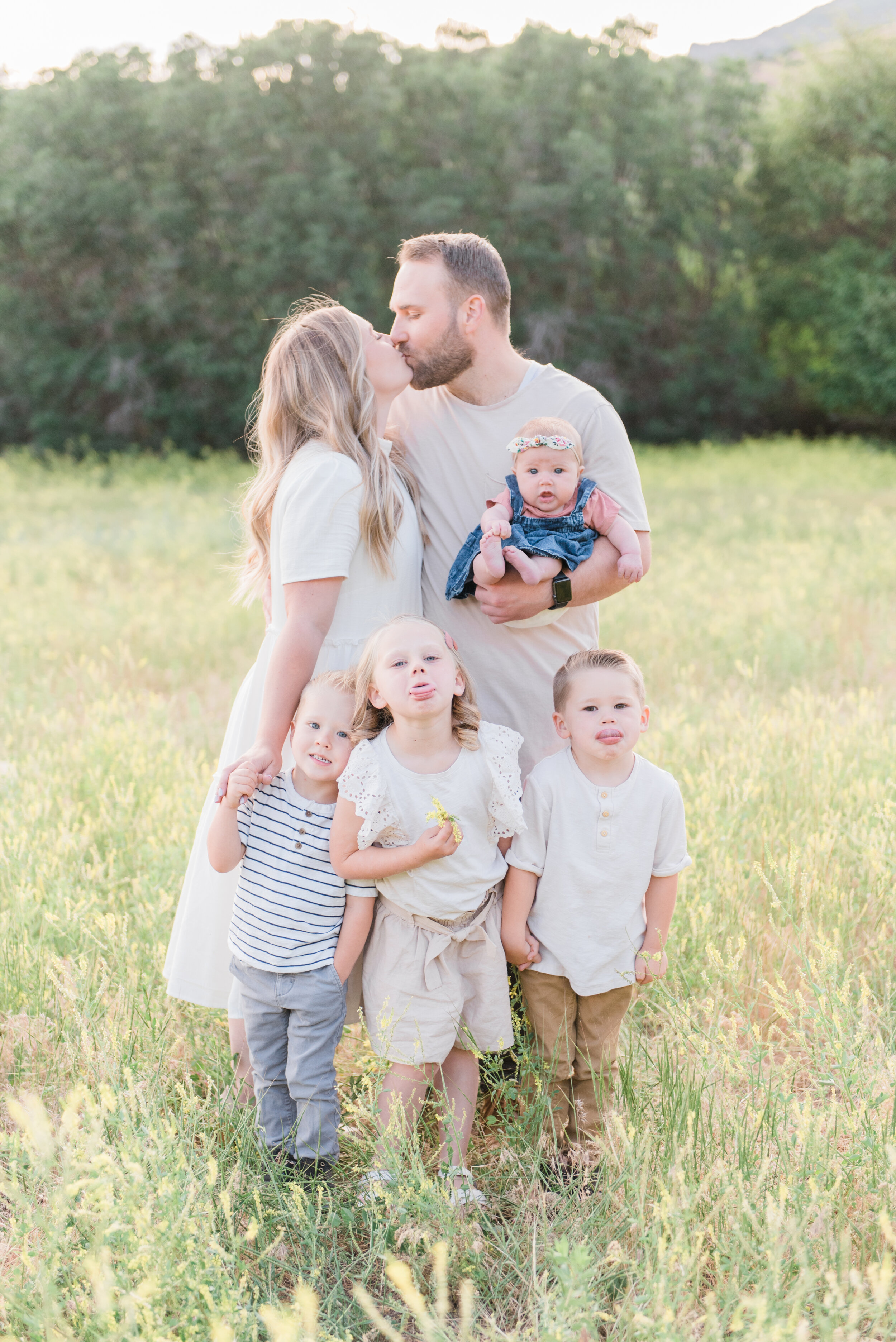  This photo by Jacquie Erickson captures the children's personalities while highlighting the love between the parents. Light outfits meadow photo location family of six sicking out tongues #candidphoto #familyofsixphotos #lightfamilyoutfits 