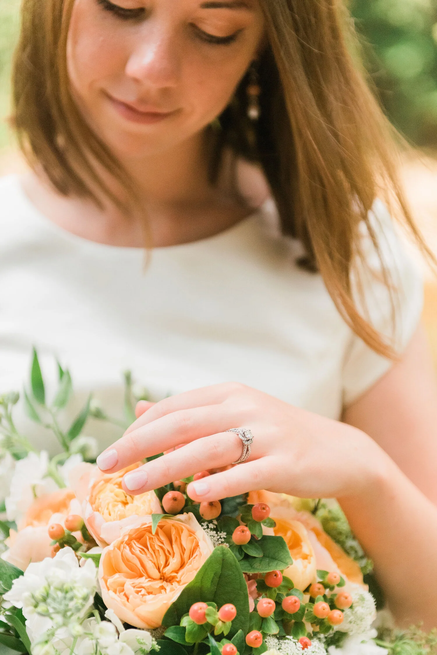  A stunning bride smiles at her wedding bouquet while taking pictures in Logan Square Park in Philadelphia, PA. Peony bouquet wedding ring inspiration maryland photographer outdoor wedding photographer Jacquie Erickson photography hair down for weddi
