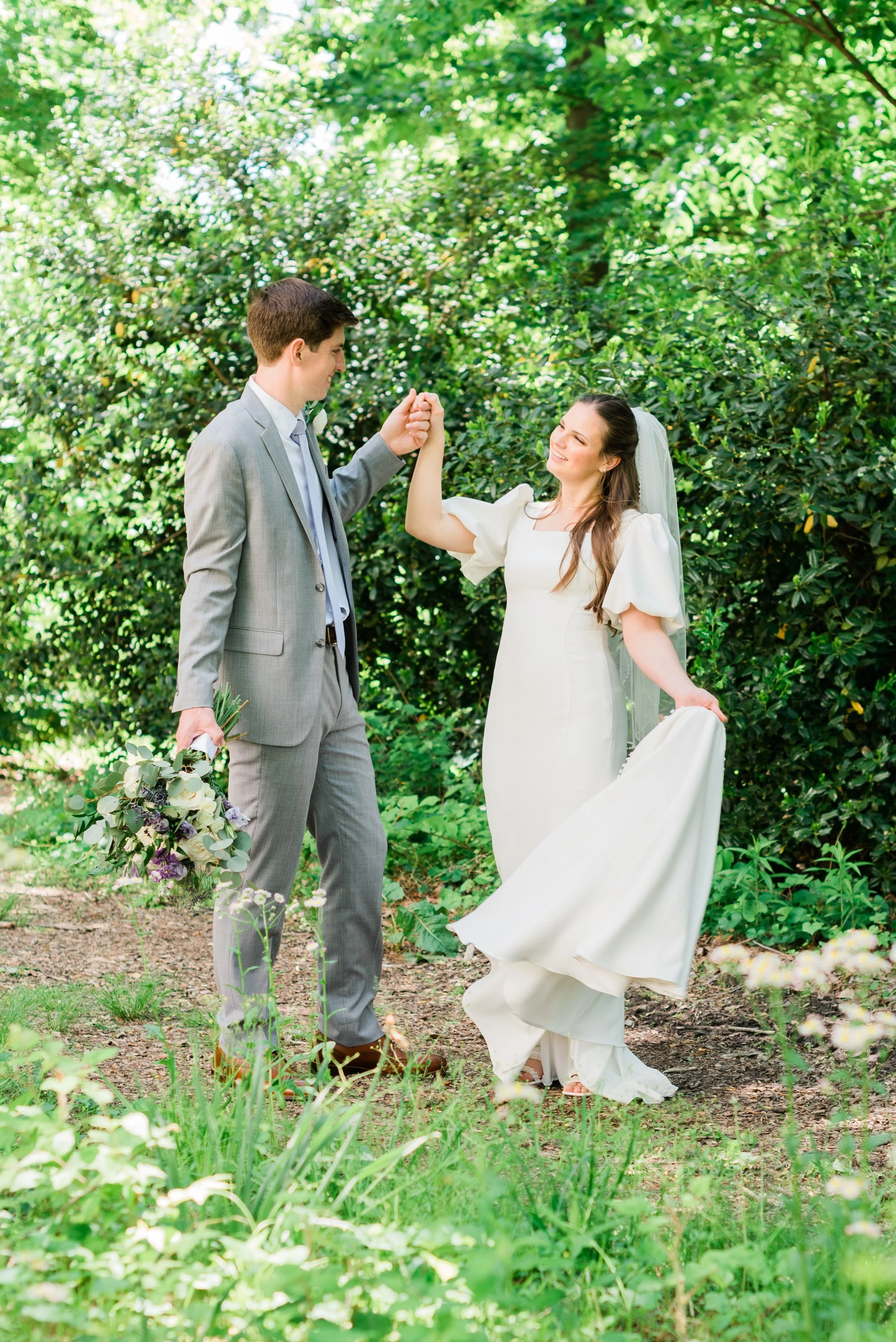  a groom dances with his bride in a forest area while holding the bouquet by Jacquie Erickson Photography. dancing newlyweds strappy bridal shoes veil sheer #JacquieEricksonPhotography #JacquieEricksonWeddings #SpringDCWedding #SpringWedding #LDSTemp