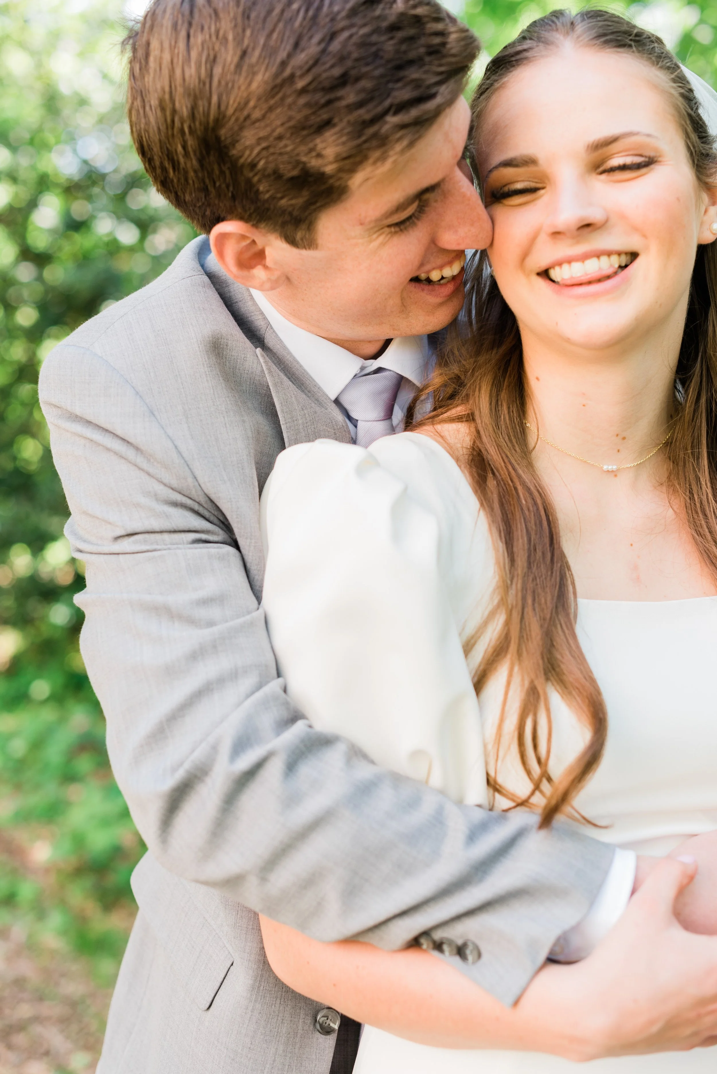  A bride laughs as she snuggles into her new husband's embrace by Jacquie Erickson Photography. groom whispers sweet nothings hugging newlyweds spring wedding vibes #JacquieEricksonPhotography #JacquieEricksonWeddings #SpringDCWedding #SpringWedding 