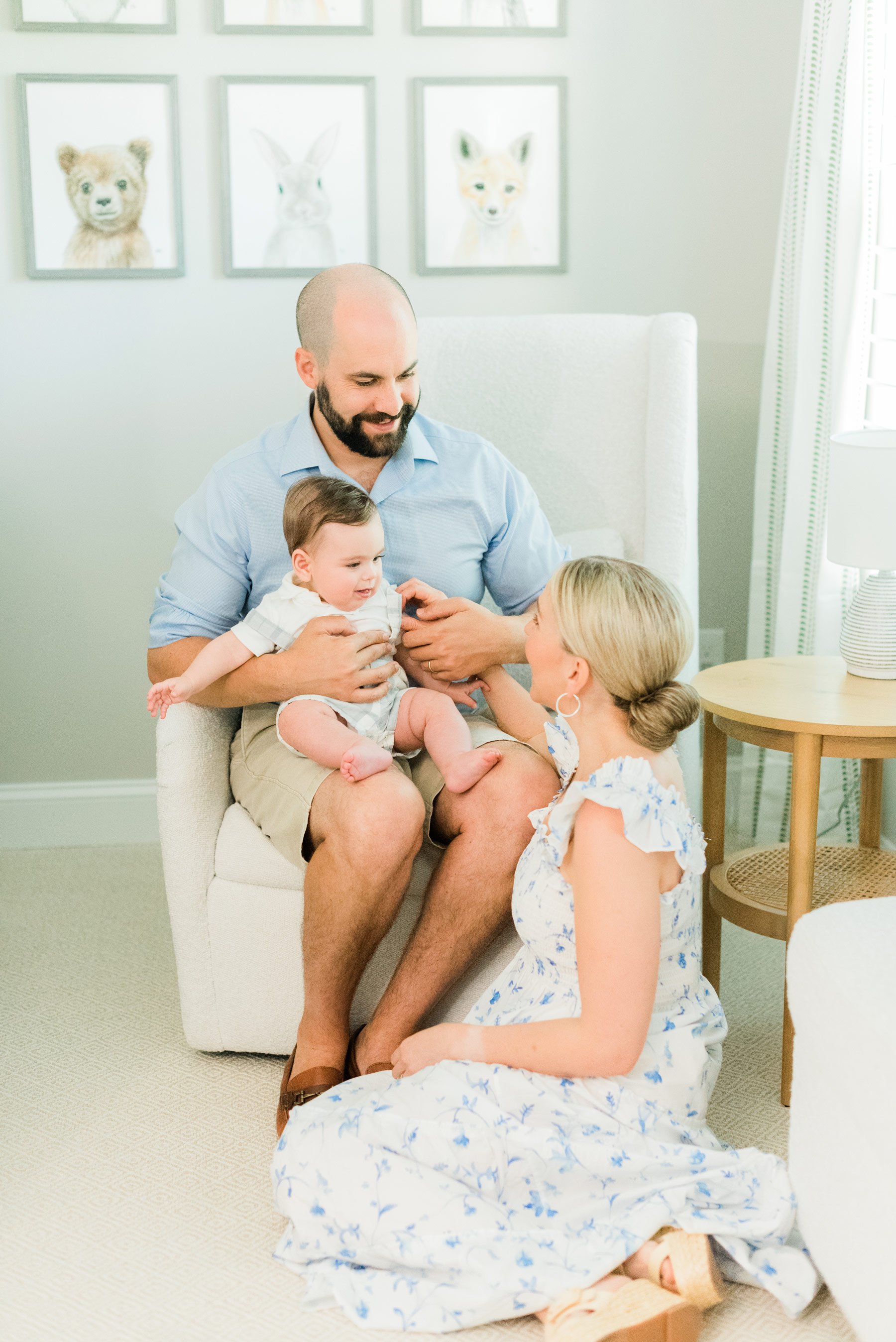  The cutest mom sits on the floor and gazes up at her husband and son during a Jacquie Erickson photography session. Soft blue outfit inspiration.&nbsp; #inhomeportraitsessions #familyphotos #portraitphotography #atlantaphotographer #jacquieerickson 