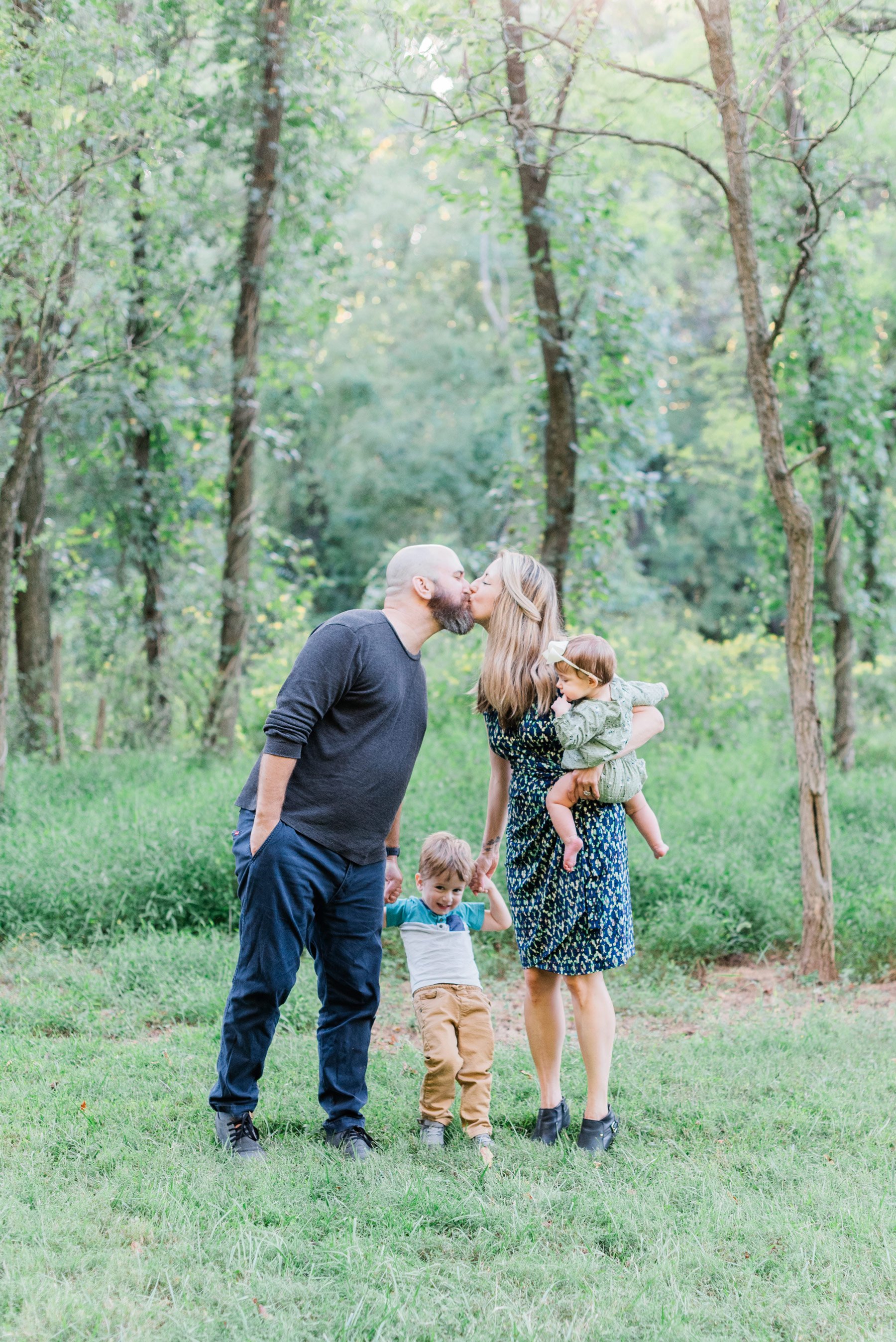    I love the wispy trees behind this sweet family of four as mom and dad share a kiss. #peachtreecityphotographer #familyphotographersenoia #outdoorfamilyphotos #familyphotoswithkids #fayettevillefamilyphotographer #fallfamilyphotographer #georgiafa