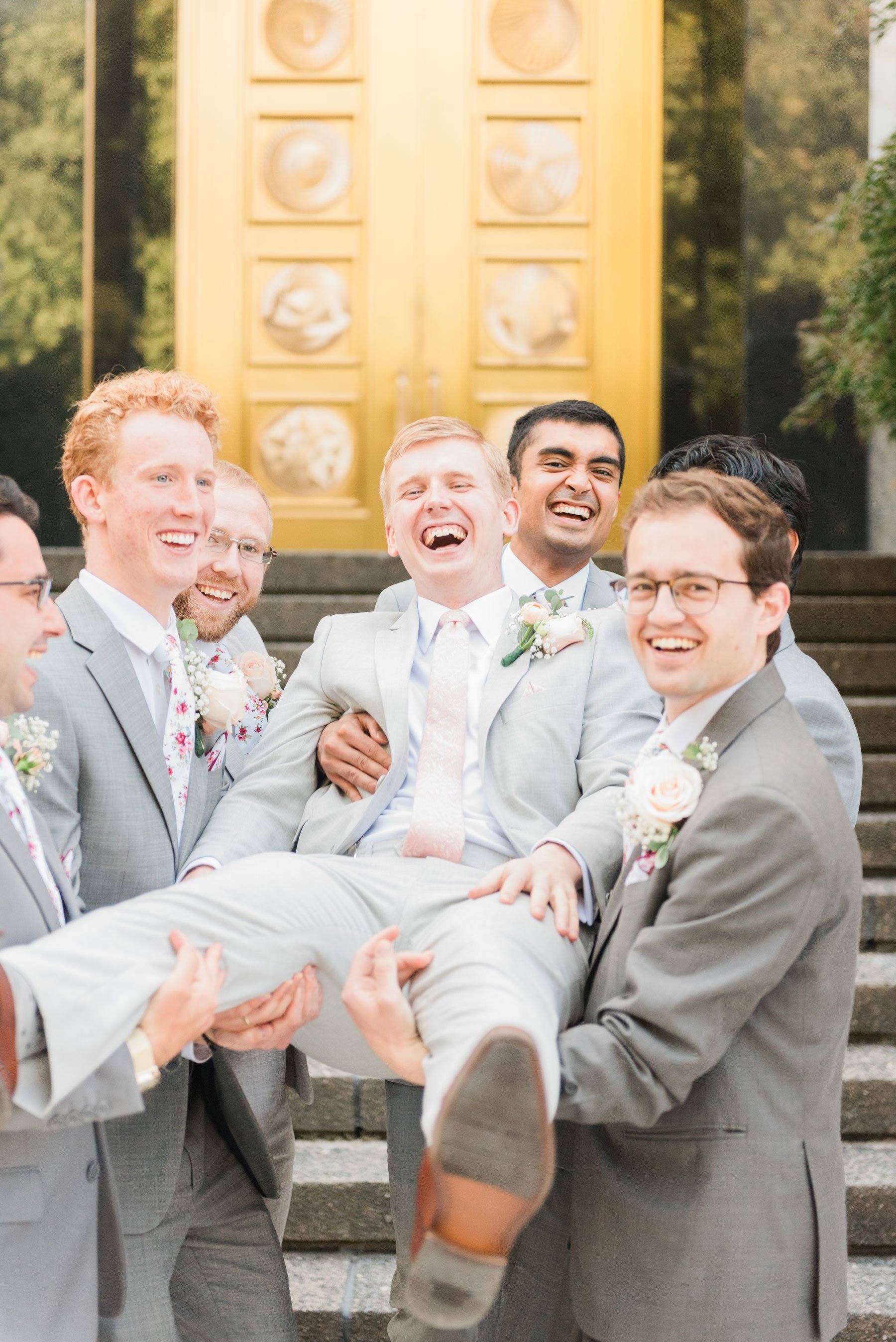    Fun groomsmen lift the groom for a silly bridal party pose outside of the lds temple doors. #washingtondctemple #washingtondcweddingphotographer #dcwedding #pinkwedding #ldsweddingphotographer #pinkweddingbouquet #washingtondctempleexit #eastcoast