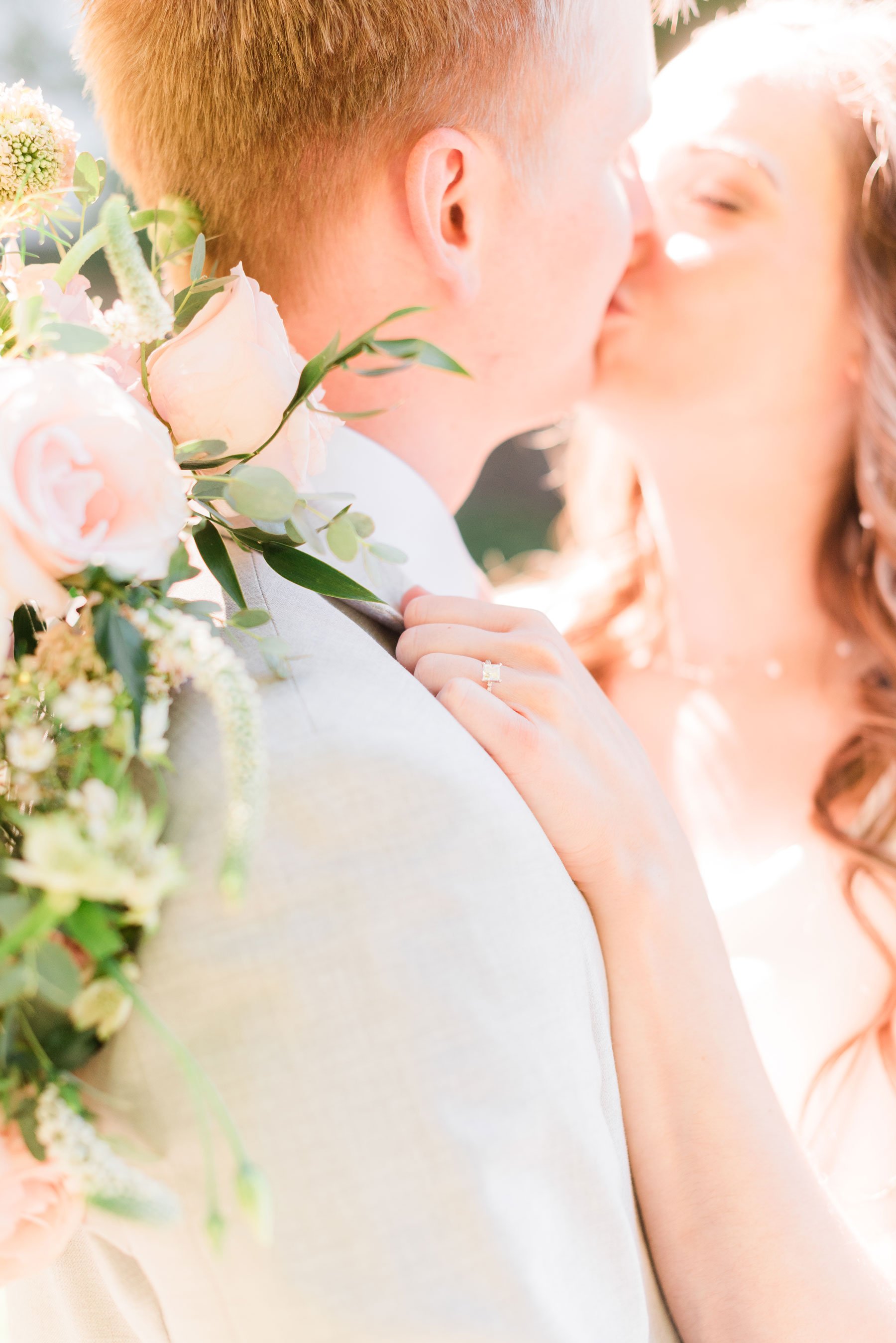    The newlyweds share a kiss in this bright and airy wedding portrait featuring her rose bouquet. #washingtondctemple #washingtondcweddingphotographer #dcwedding #pinkwedding #ldsweddingphotographer #pinkweddingbouquet #washingtondctempleexit #eastc