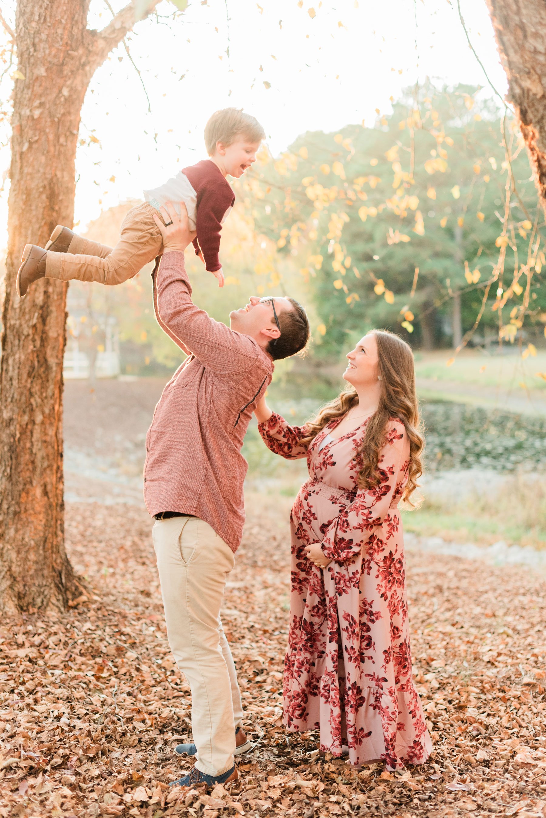  A father lifts his young son above him while his pregnant wife stands behind smiling up and him during their family maternity photo shoot. Georgia Maternity photos&nbsp; #familymaterintyphotos #pregnacyphotoshoot #familyof4 #peachtreecity #atlantafa