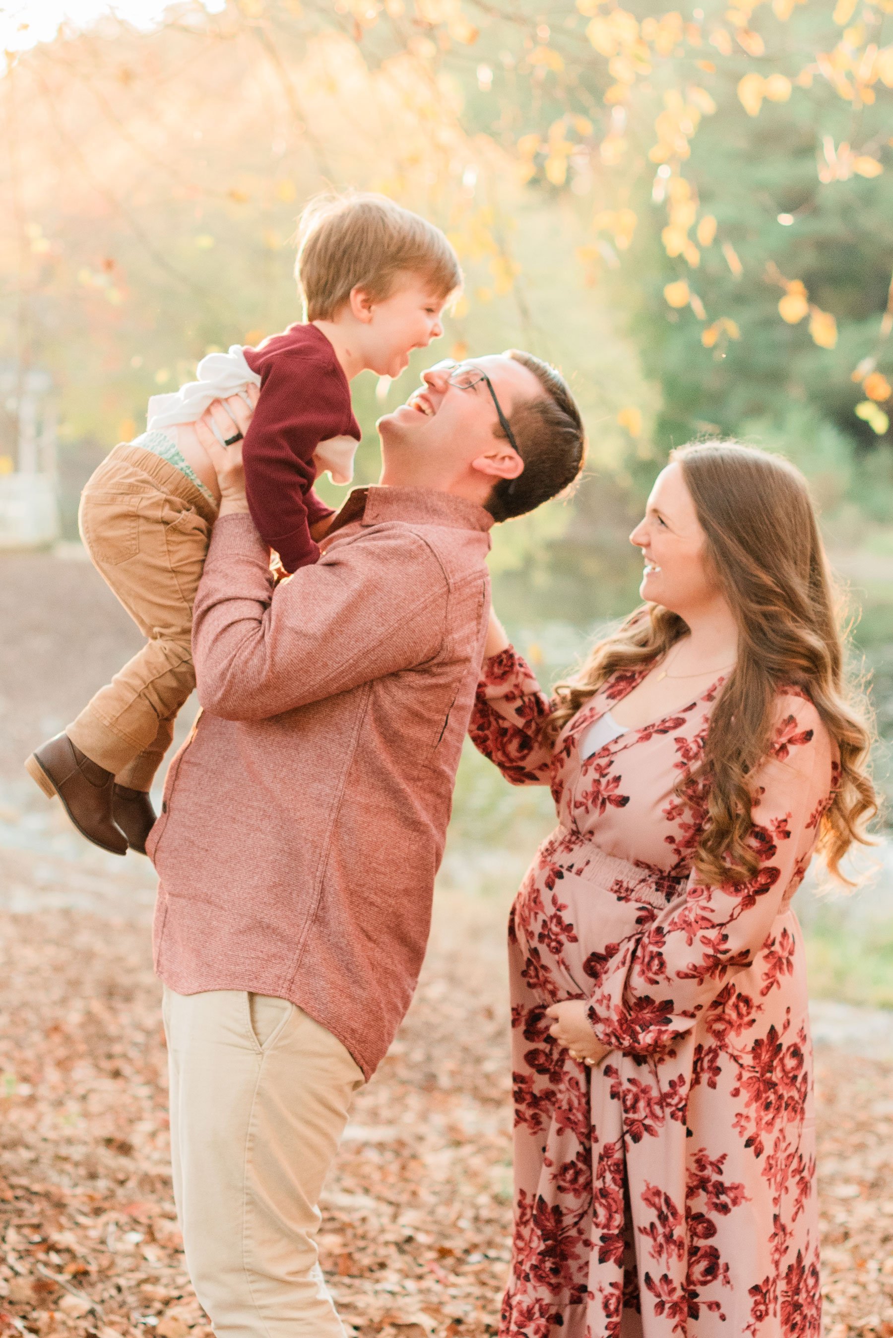  A father lifts his young son while his pregnant wife stands behind smiling up and him during their family maternity photo shoot. Georgia Maternity photos&nbsp; #familymaterintyphotos #pregnacyphotoshoot #familyof4 #peachtreecity #atlantafamilyphotog