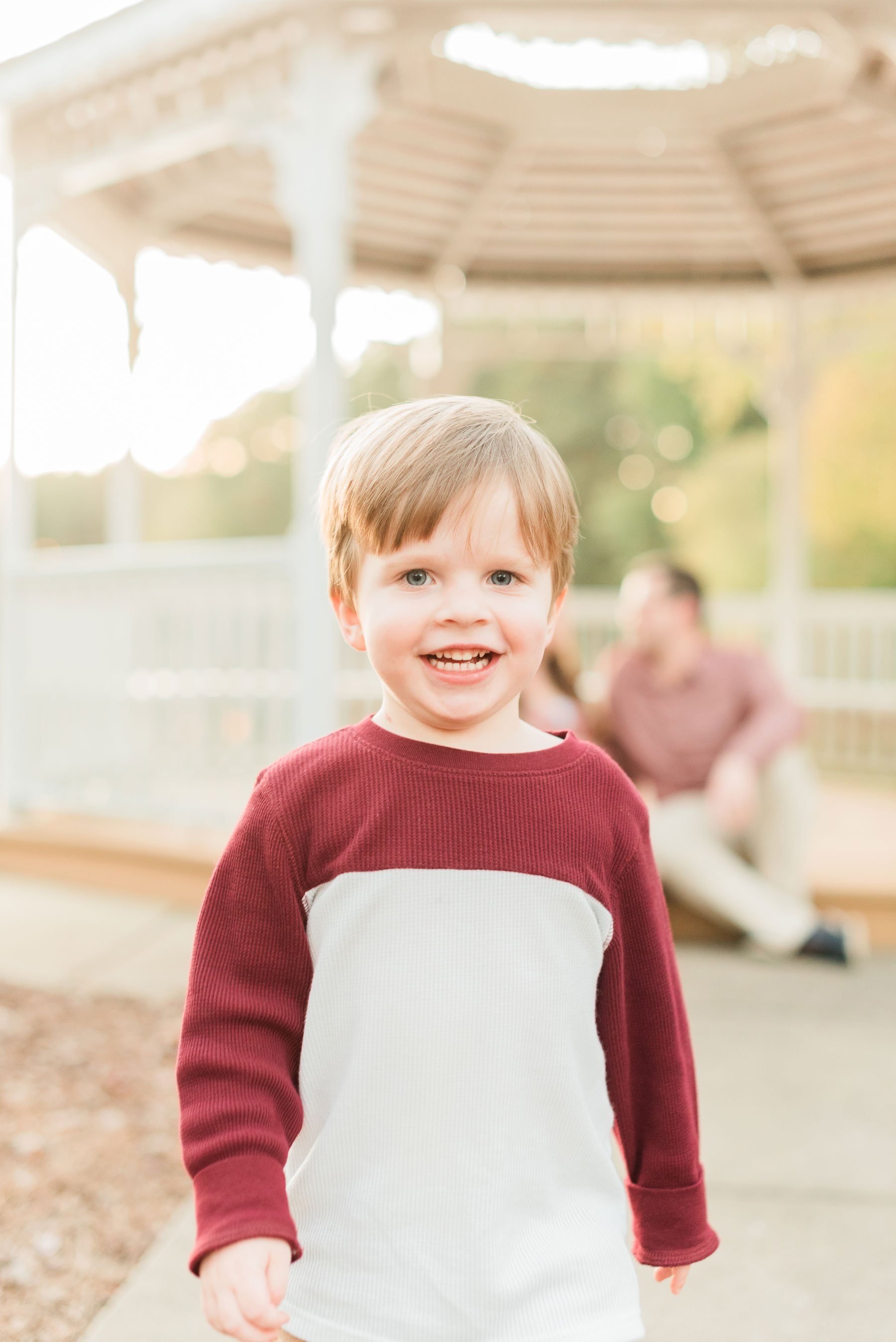  A strawberry-blonde two-year-old boy wearing a red and white shirt smiles. Atlanta Georgia Sandy Springs Sharpsburg Roswell&nbsp; #familymaterintyphotos #pregnacyphotoshoot #littleboyphoto&nbsp; #peachtreecity #atlantafamilyphotographer #jacquieeric