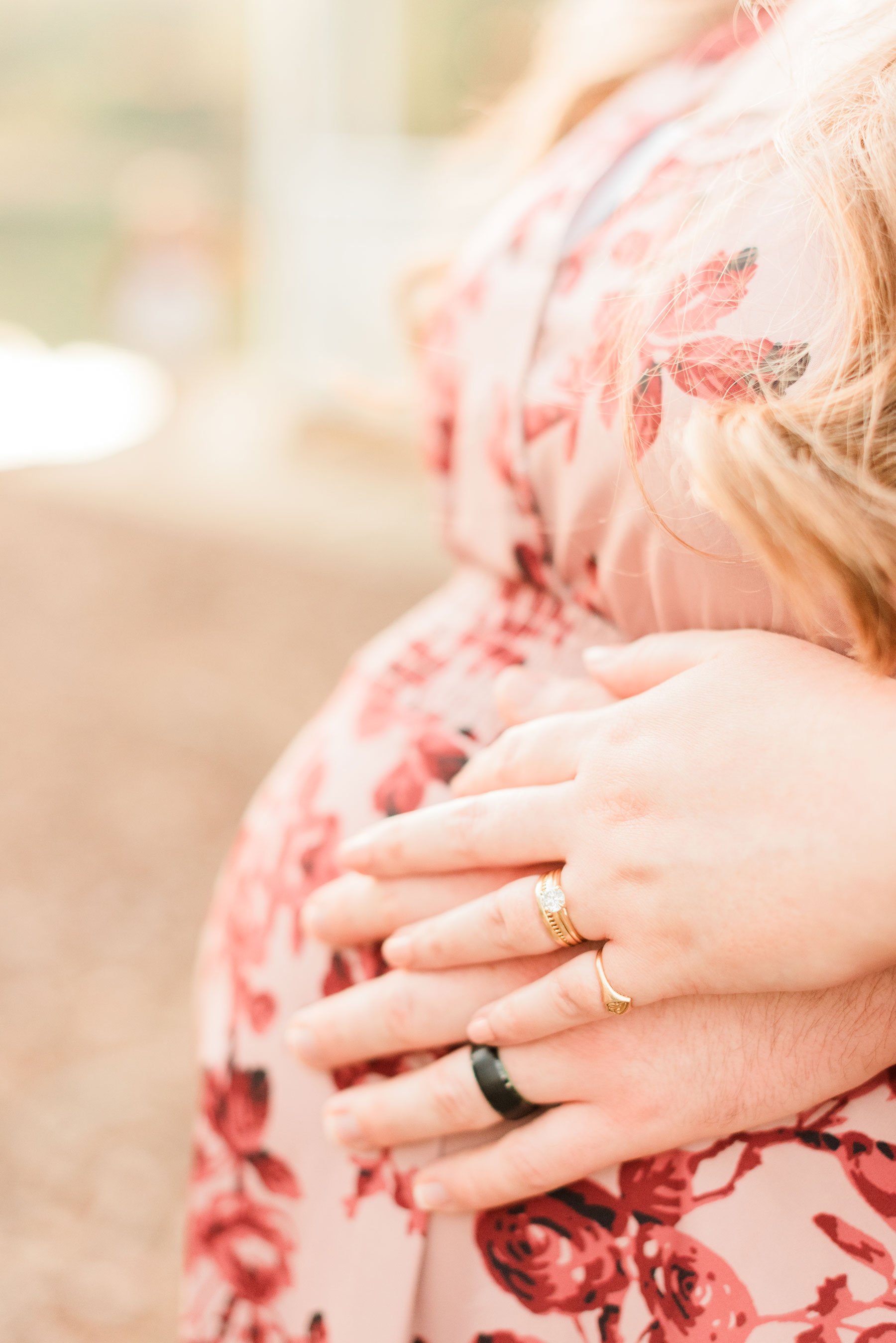  A husband and wife’s left hand with their wedding rings in focus rests on her pregnant belly. Hands-on baby bump wedding rings #familymaterintyphotos #pregnacyphotoshoot #peachtreecity #atlantafamilyphotographer #jacquieerickson #babybump 