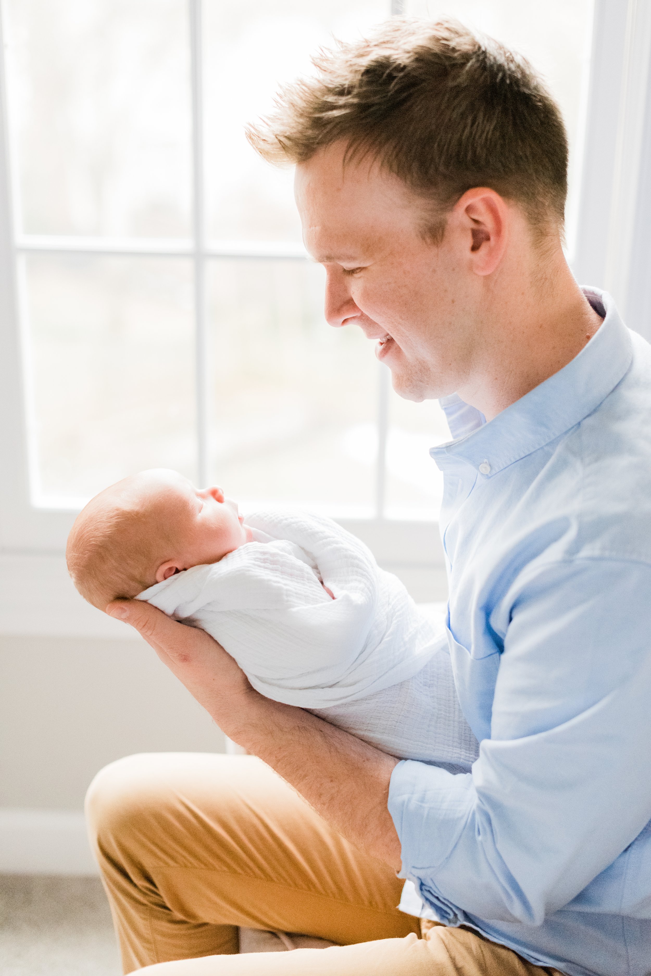  A new father looks lovingly at his new baby in his hands in a personalized photo captured by Jacquie Erickson, an Atlanta-based photographer. New parent photo personalized photoshoot #atlantafamilyphotographer #familiesofinstagram #AtlantaPortraits 