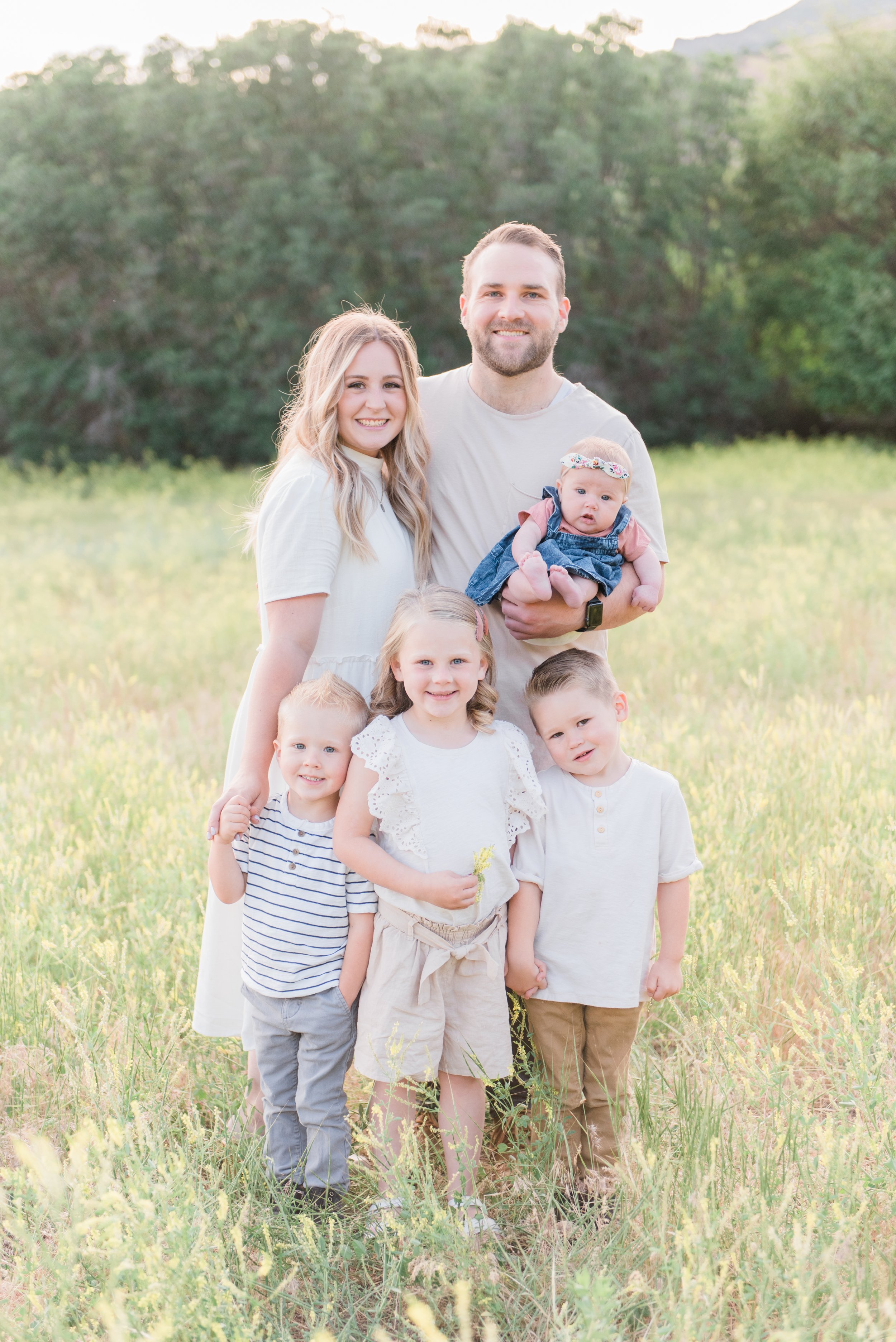  A young family of four smiles together in a meadow during a family photo shoot by Jacquie Erickson, an Atlanta-based photographer. personalized photoshoot #atlantafamilyphotographer #familiesofinstagram #familypics #GeorgiaFamilyPhotographer 
