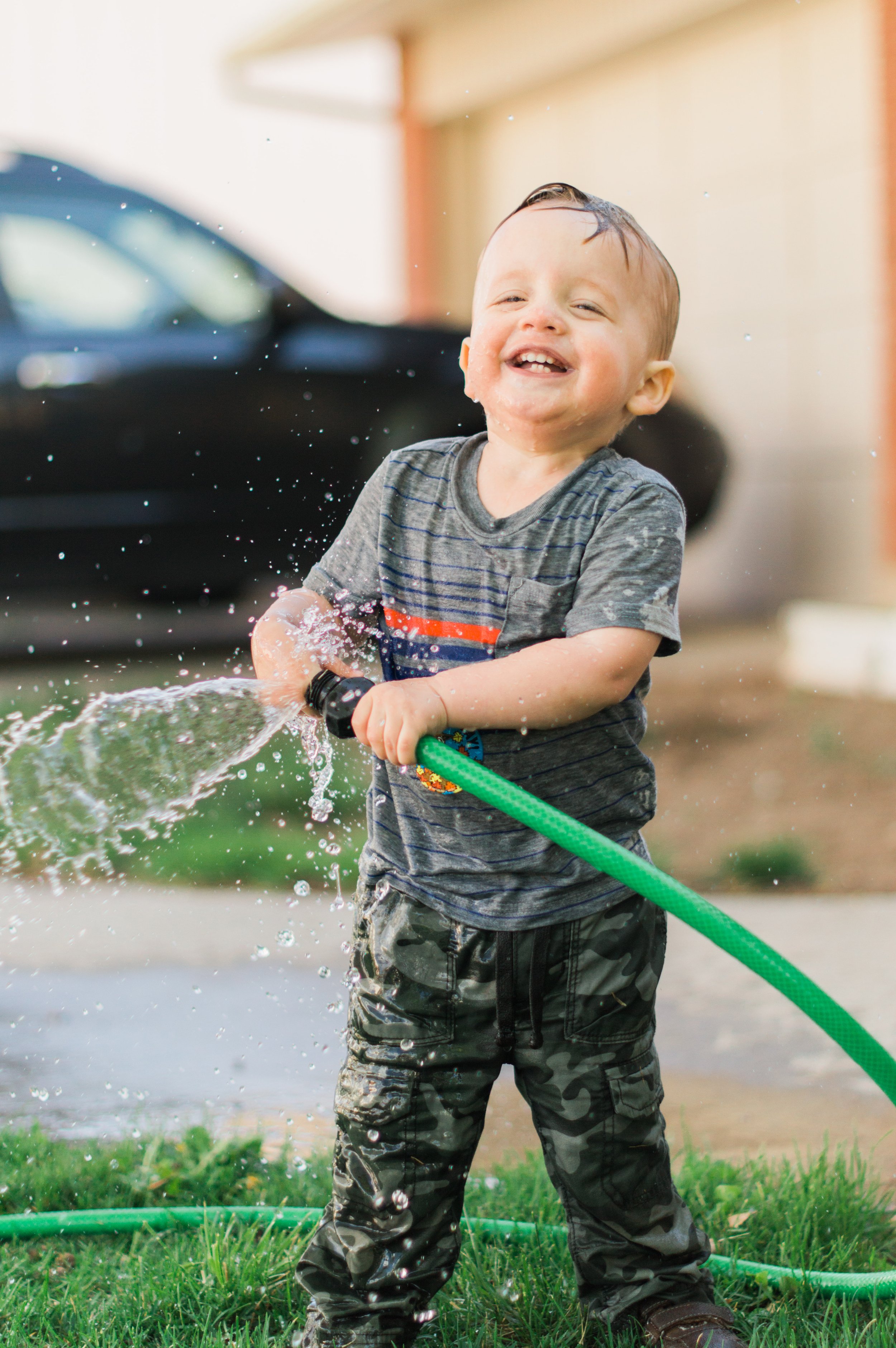  This photo captures the mischief and joy of this boy as he is soaked by a hose on a beautiful summer day as they wash the car. Happy boy cash wash candid shot wet little boy #candidkidsphoto #daddyshelper #midlaugh #summertime #summercarwash #georgi