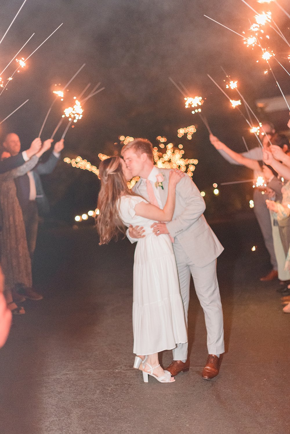  A bride and groom kiss each other as they stand under an arch of sparklers while exiting their reception. Wedding sparklers wedding send-off wedding must-haves document your wedding Peachtree City Senoia Newnan#atlantaweddingphotographer #memorablew