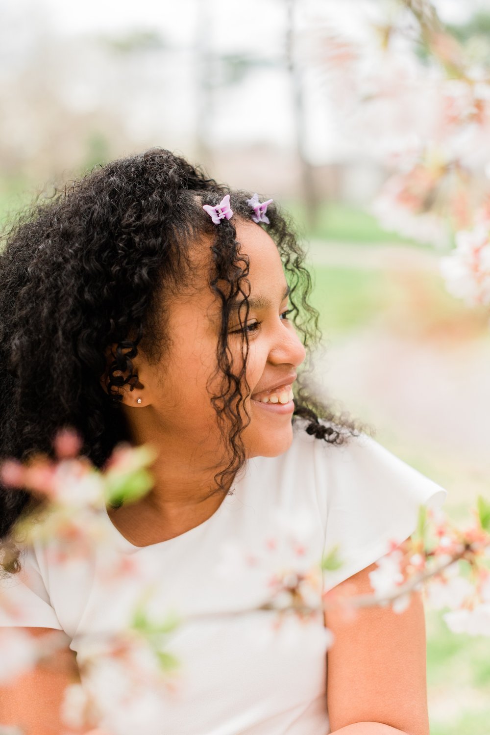  A little girl with curly black hair smiles to the side, showing her cute profile in a portrait photo captured by Peachtree City photographer, Jacquie Erickson Senoia&nbsp; Newnan&nbsp; Alpharetta Children's portraits capture their childhood #childpo