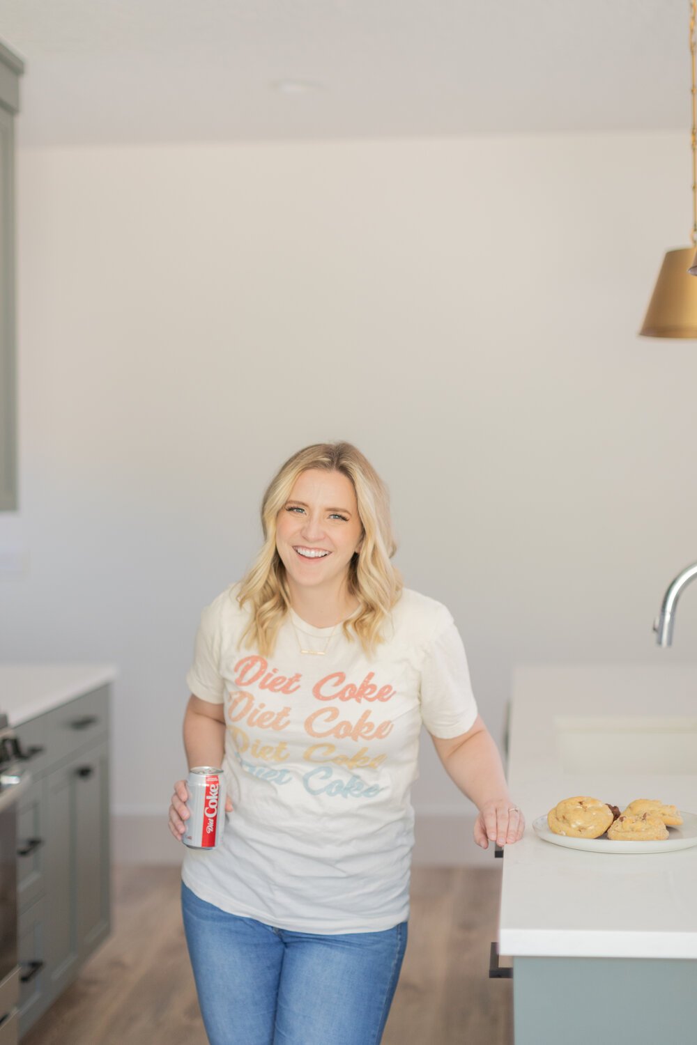  Jacquie Erickson, an Atlanta photographer and small business coach poses in a kitchen holding a Diet Coke and a plate of cookies. Client questionnaire Momtog course streamline workflow small business helpers #planoly #pixiset #tailwind #diyphotograp